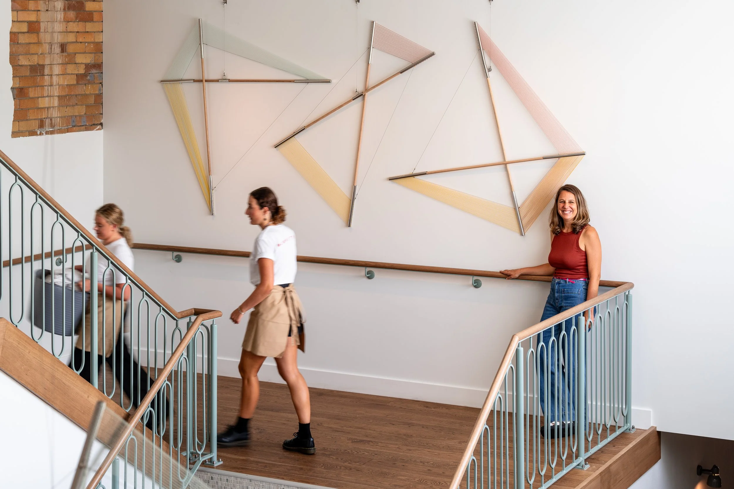 People walking on a staircase with abstract art on the wall.