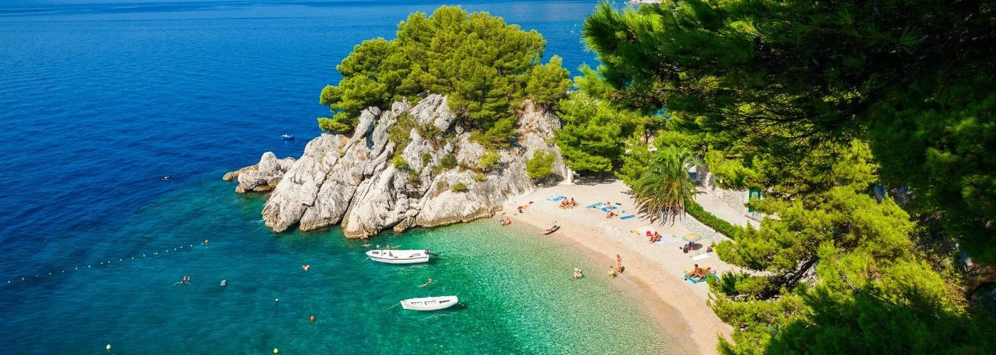 Green and blue waters of a bay with people sunbathing and swimming