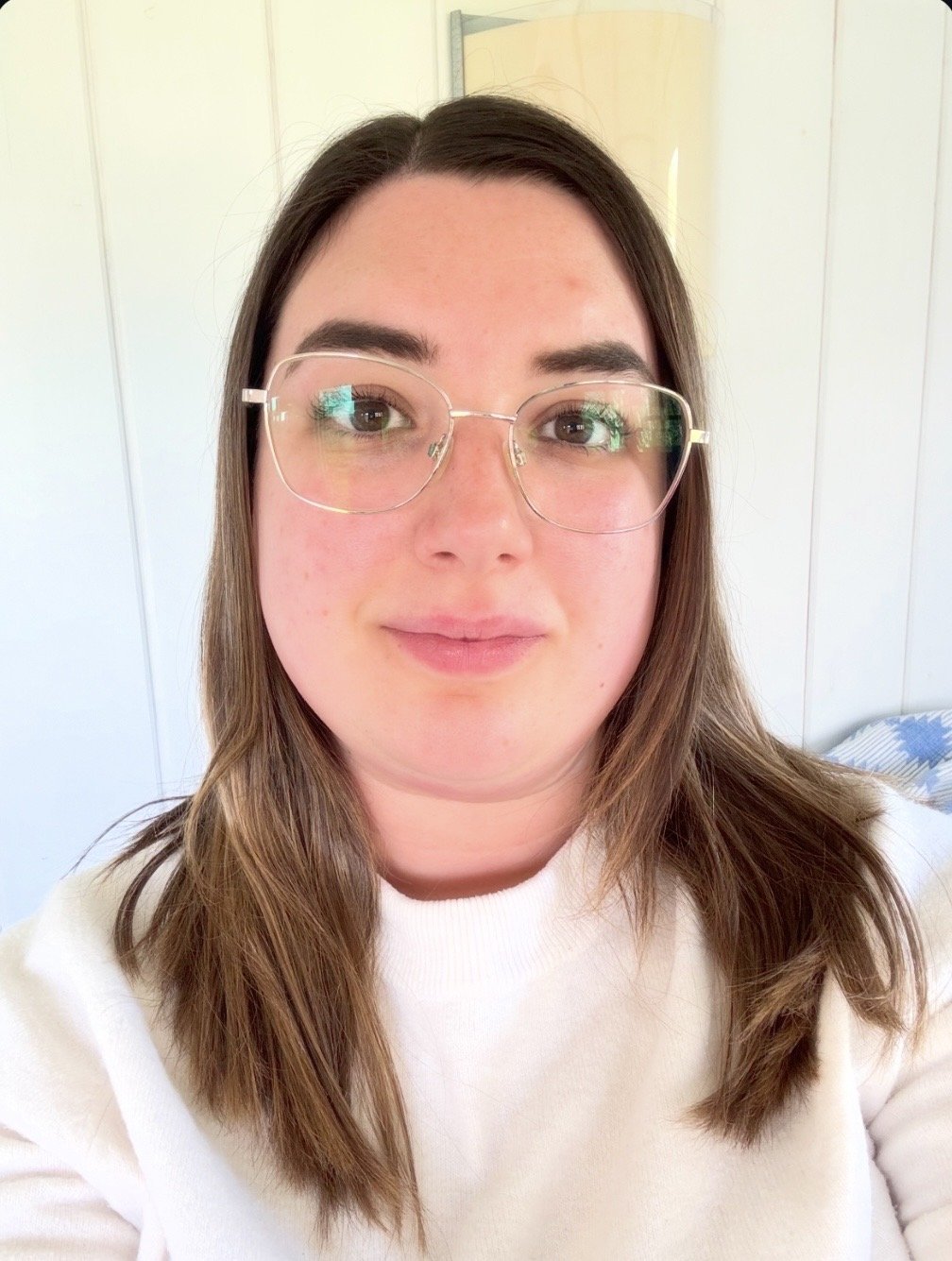 A woman with long brown hair and glasses in a light-colored room. Charlotte Clarke is a therapist and counsellor in Nottinghamshire supporting children, young people, and adults with their mental wellbeing.