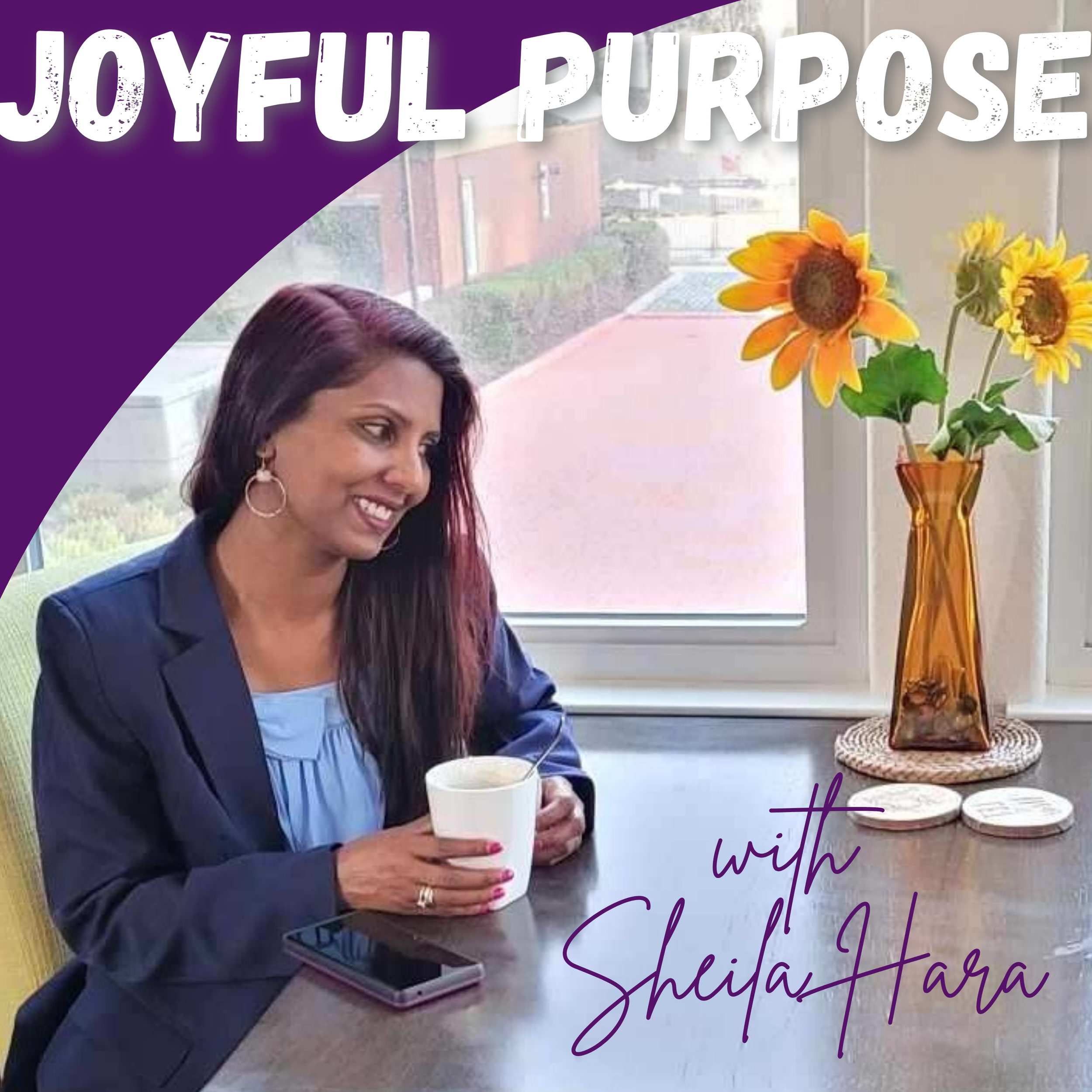 A woman with long dark hair and a navy blazer sitting at a table with a white mug. Behind her is a window with a view of a red brick building and greenery. On the table, there is an orange vase with artificial sunflowers and a few coasters. The image has purple and white text that reads 'Joyful Purpose with Sheila Hara.'