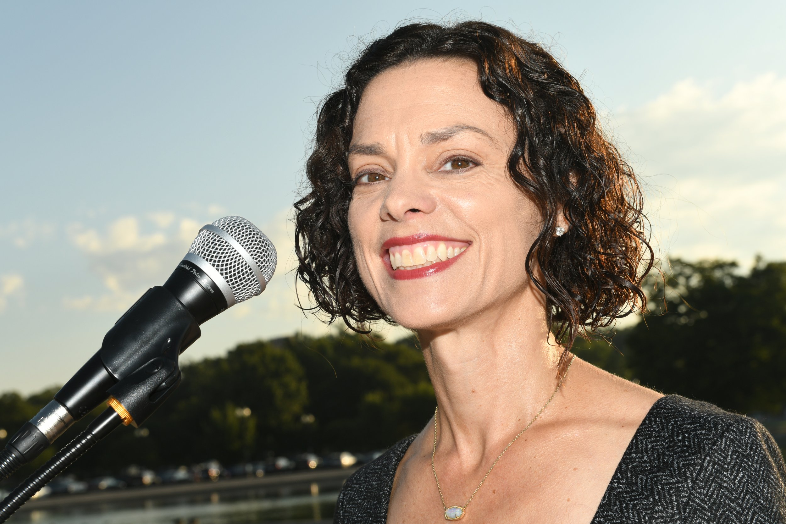 SkillsUSA Executive Director Chelle Travis A speaks into a microphone at an outdoor event or reception.