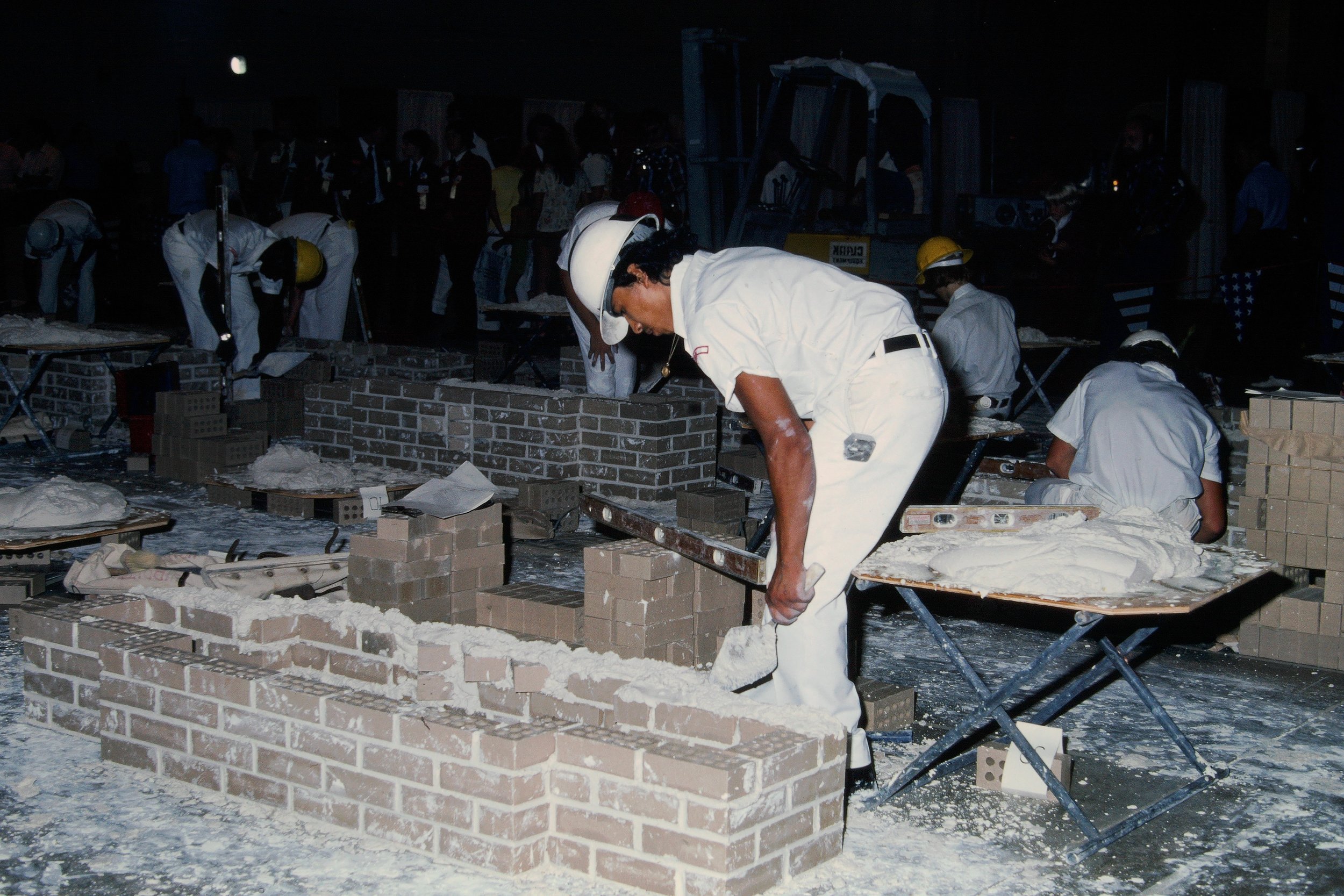  A student leans over to lay bricks during a hands-on masonry skills competition. 