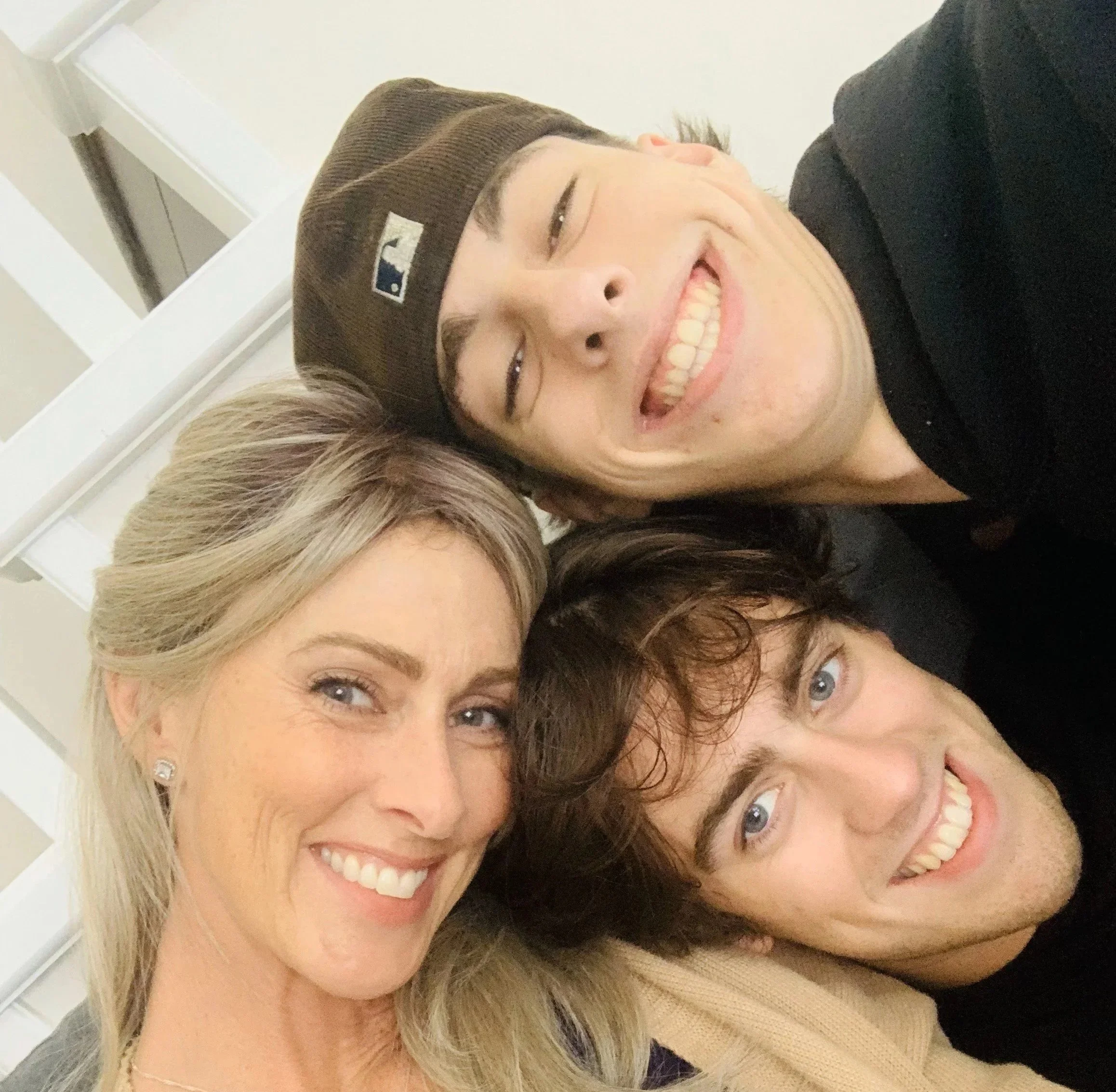 A group of three people taking a selfie, smiling, in an indoor setting.