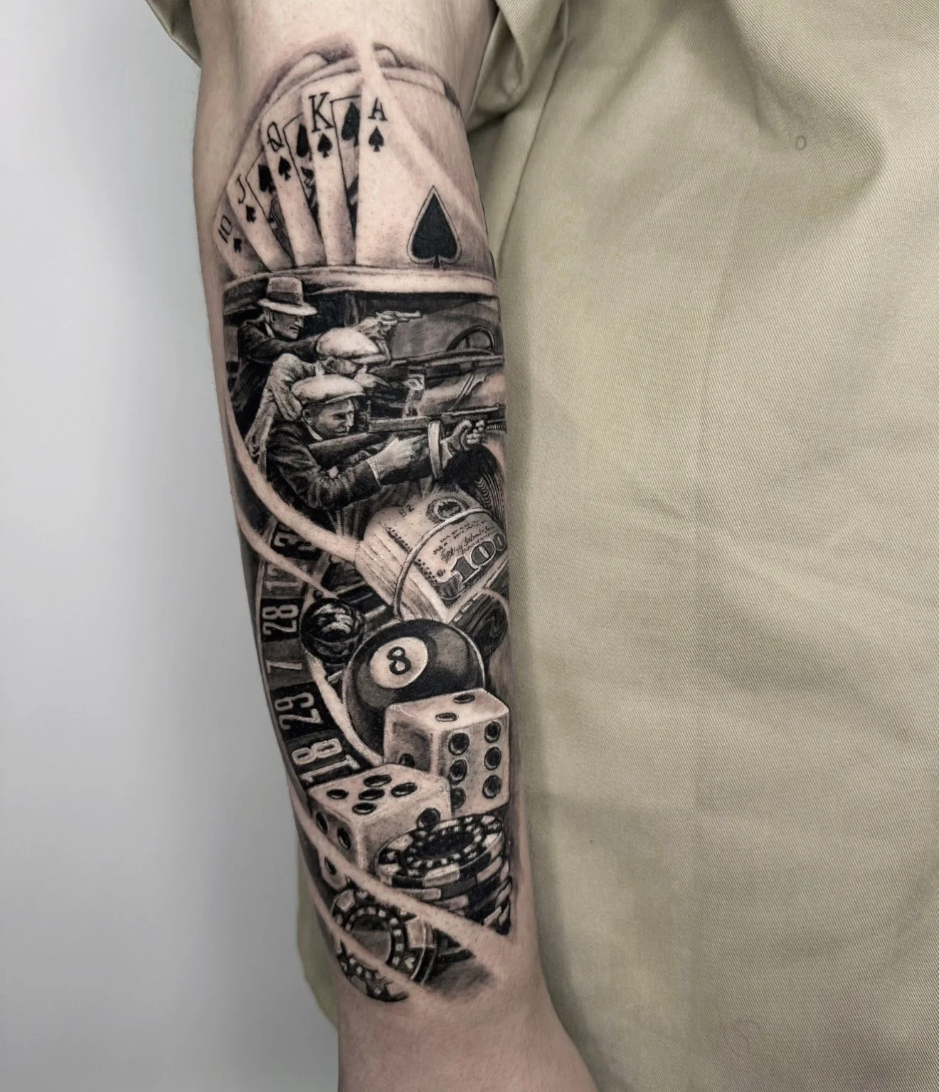 Black and grey gambling sleeve tattoo with poker cards, dice and roulette