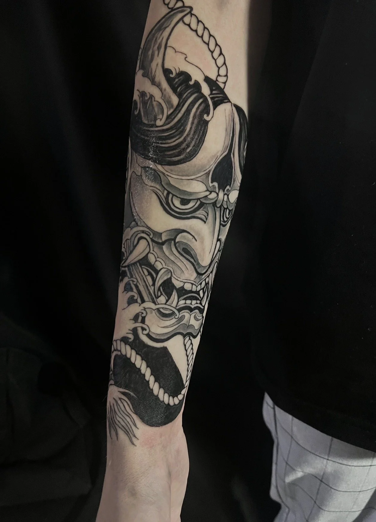 Black and gray tattoo of a traditional Japanese demon or mythological creature on a person's arm.