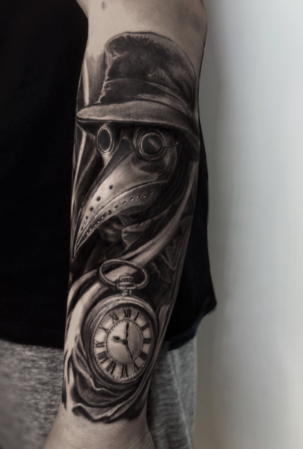 Black and grey tattoo sleeve featuring a vintage pocket watch, a cityscape with clock tower, a clock face, and a person wearing a hoodie and glasses.