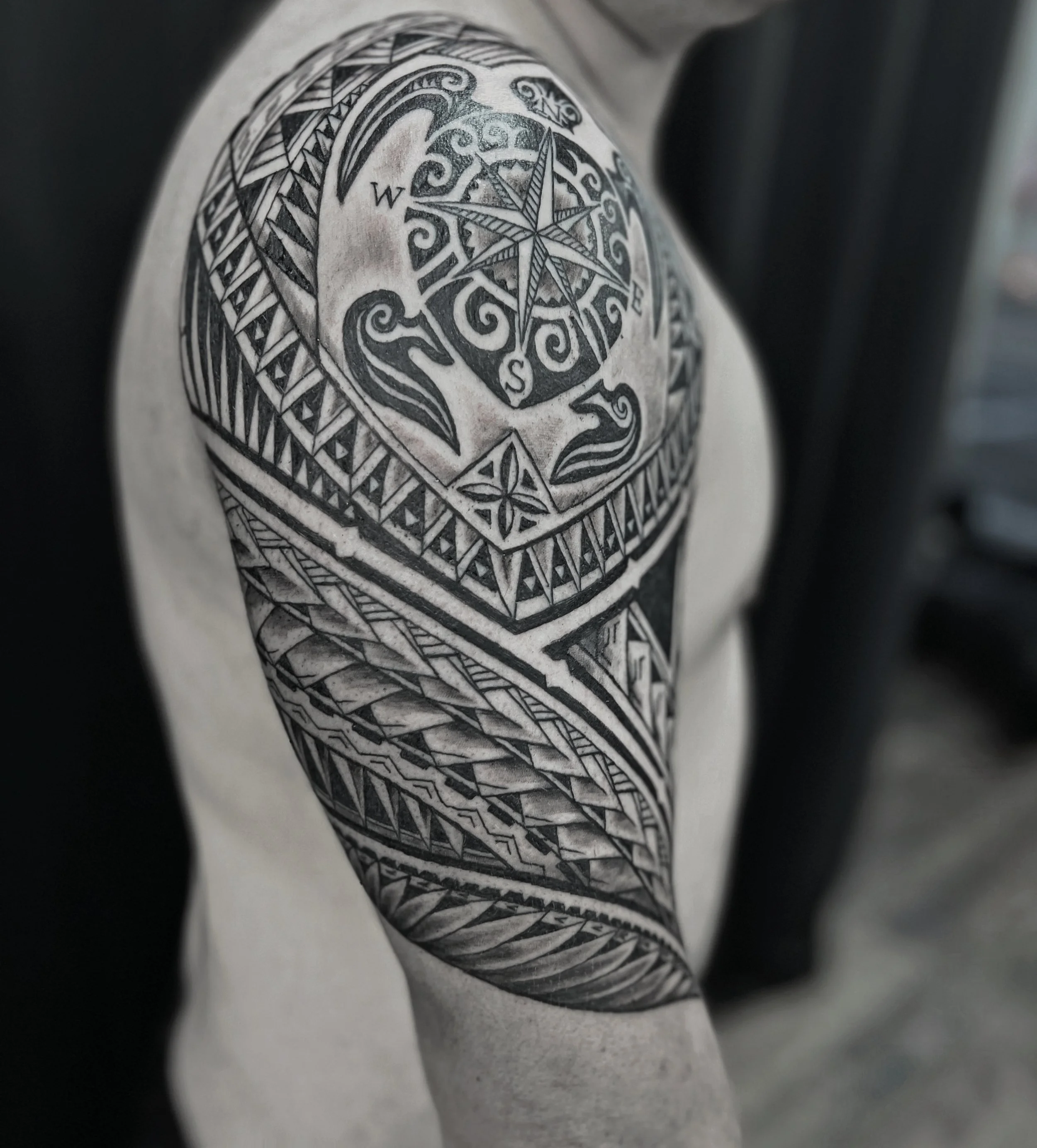 Close-up of a tattoo on a person's arm featuring a compass rose and intricate decorative patterns in black ink.