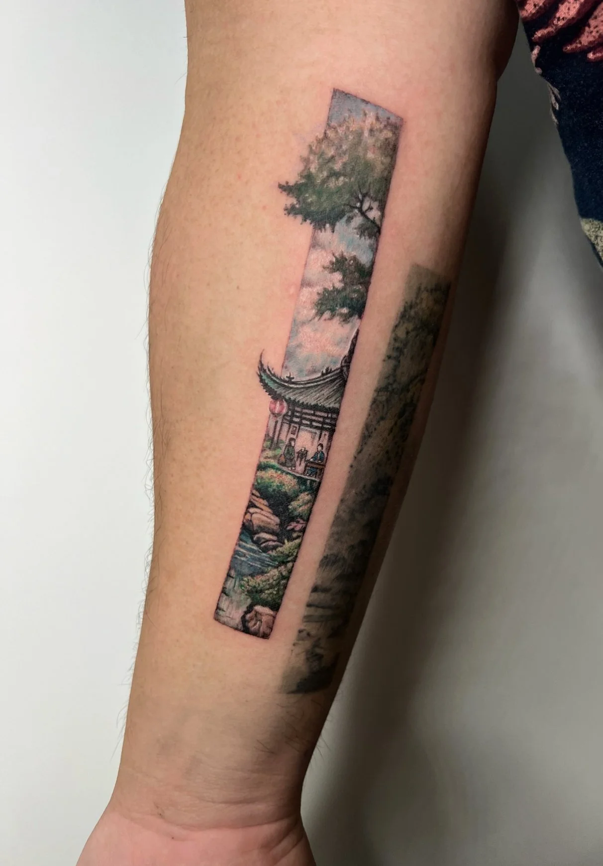 Japanese temple landscape strip tattoo on forearm