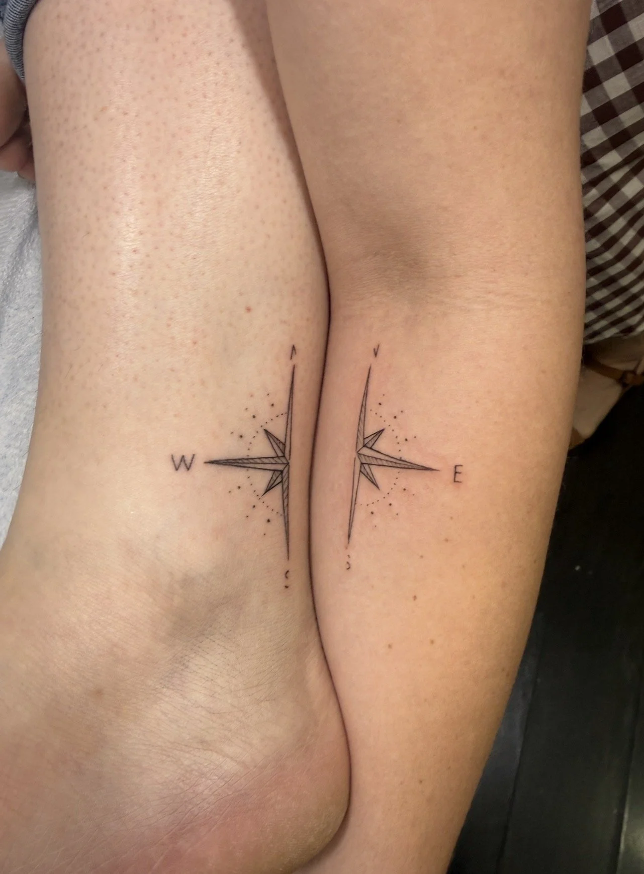 Tattoo of a compass on both thighs, with the letters W, N, E, S marking cardinal directions.