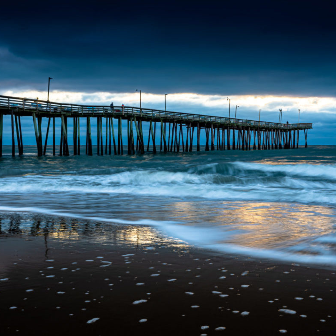 Luxury oceanfront estates and golf communities in Virginia Beach Virginia Beach Fishing Pier at dusk with waves crashing on the shore, capturing the coastal lifestyle, waterfront living, and scenic views.