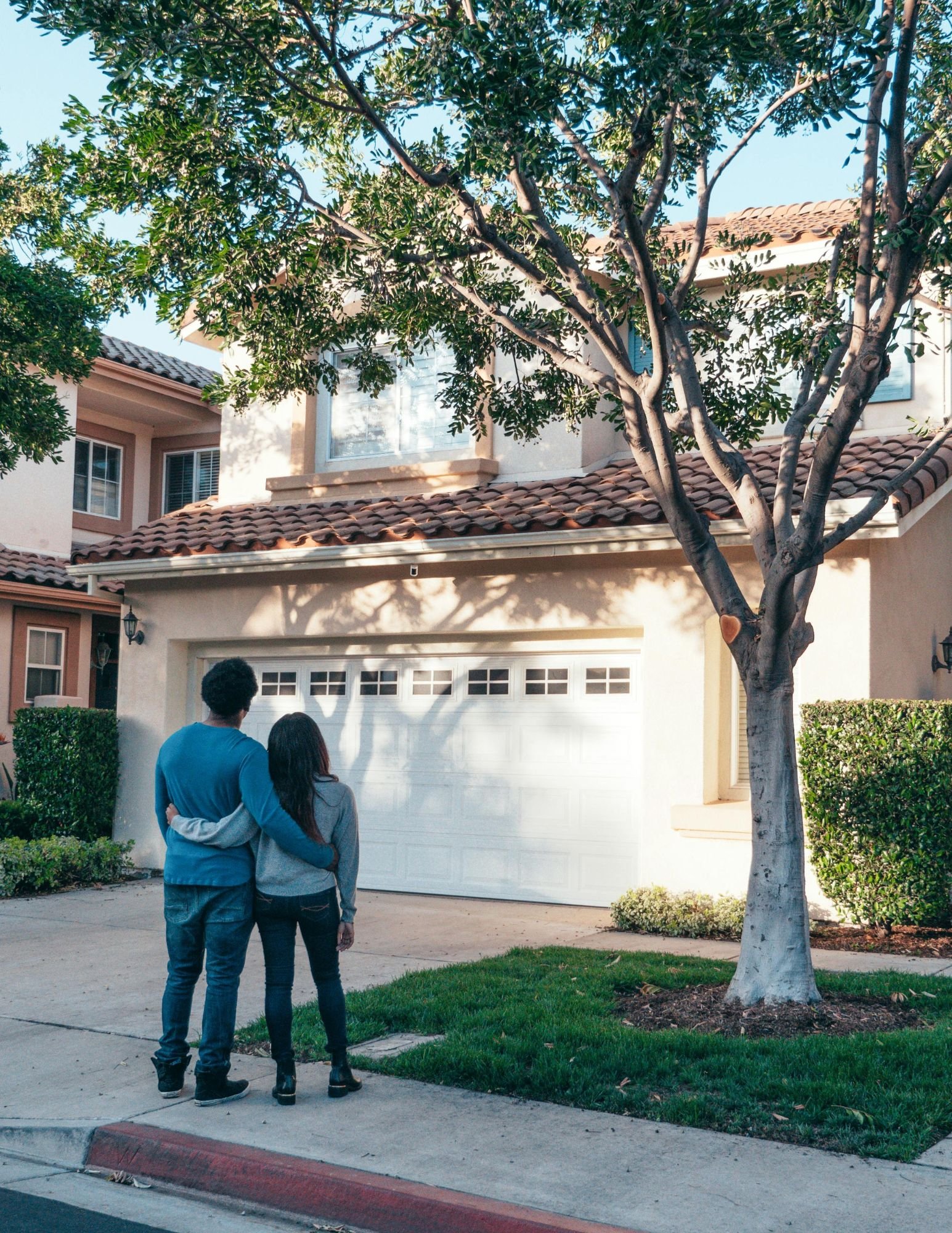 A couple embraces while admiring their sold luxury home, symbolizing success and a seamless real estate journey.