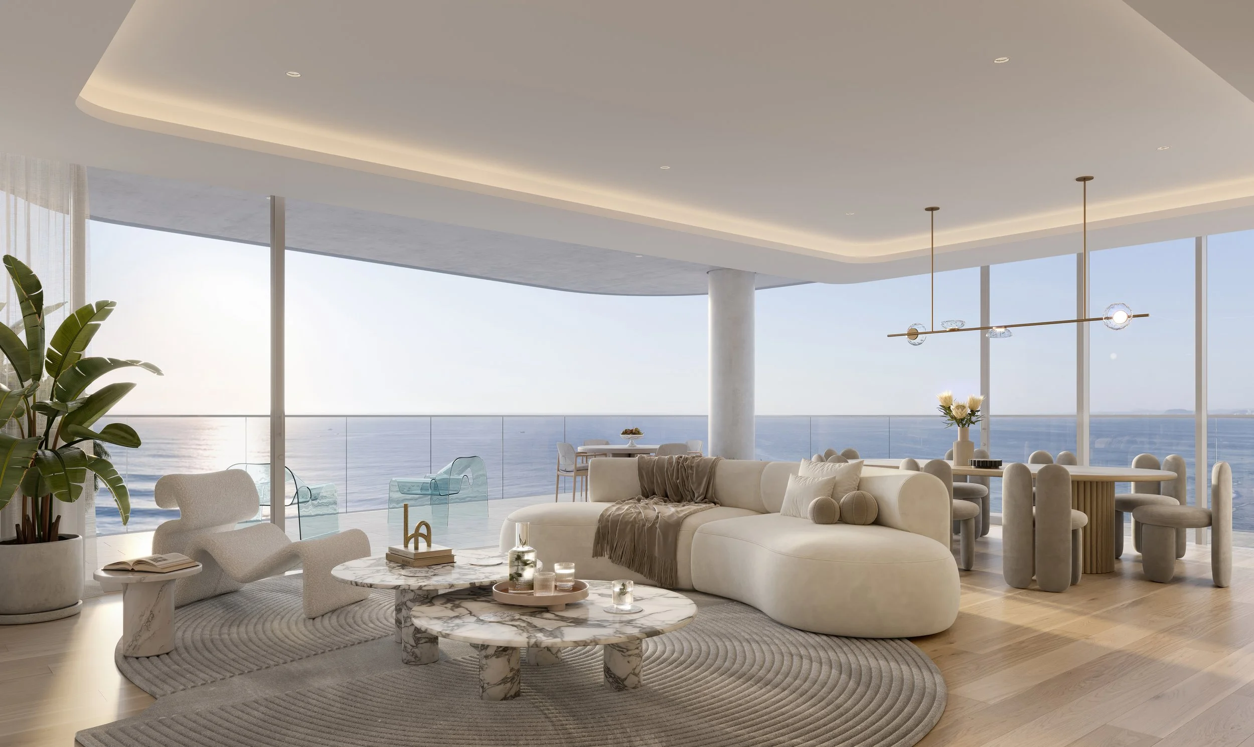 Modern interior living room with large windows overlooking the ocean, featuring a white curved sofa, marble coffee table, and dining area with a chandelier.