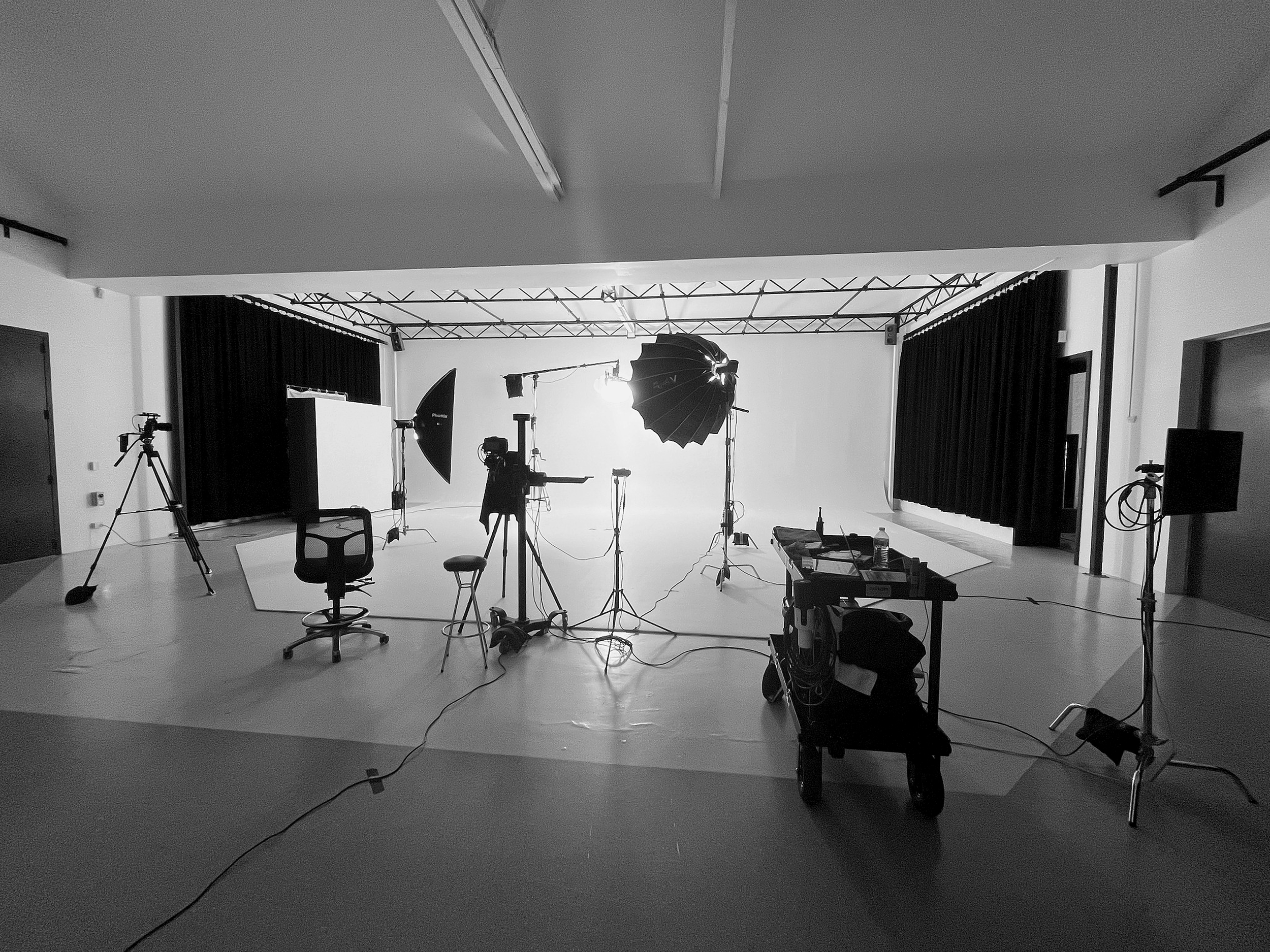 Photography studio with lighting equipment, cameras, and backdrop setup in a professional workspace.