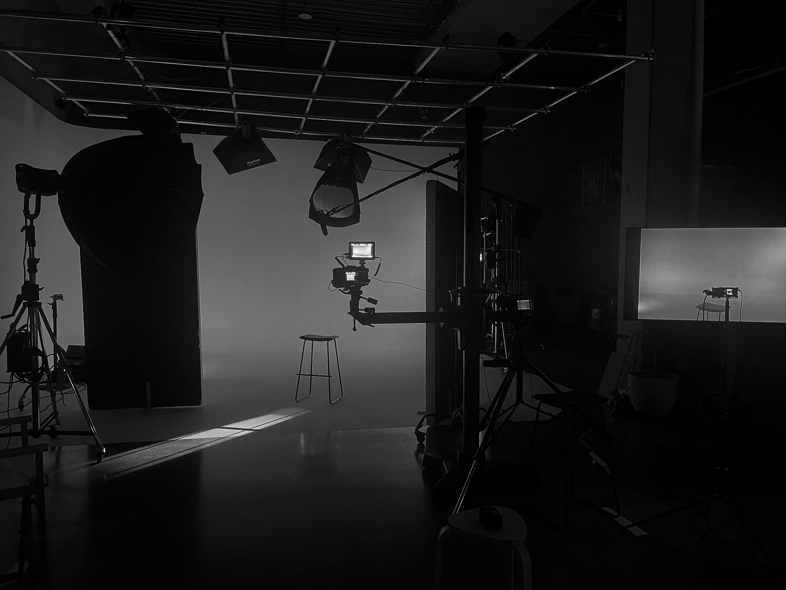 A photo studio with lighting equipment, a backdrop, and various camera accessories in a dark setting.