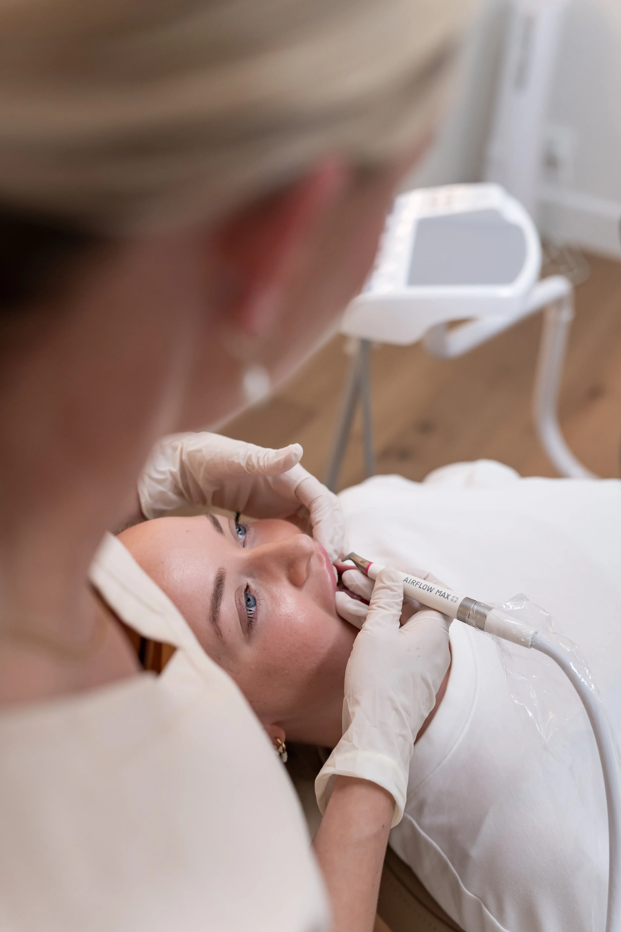 Medical professional performing a procedure on a young woman lying on a bed in a clinical setting.