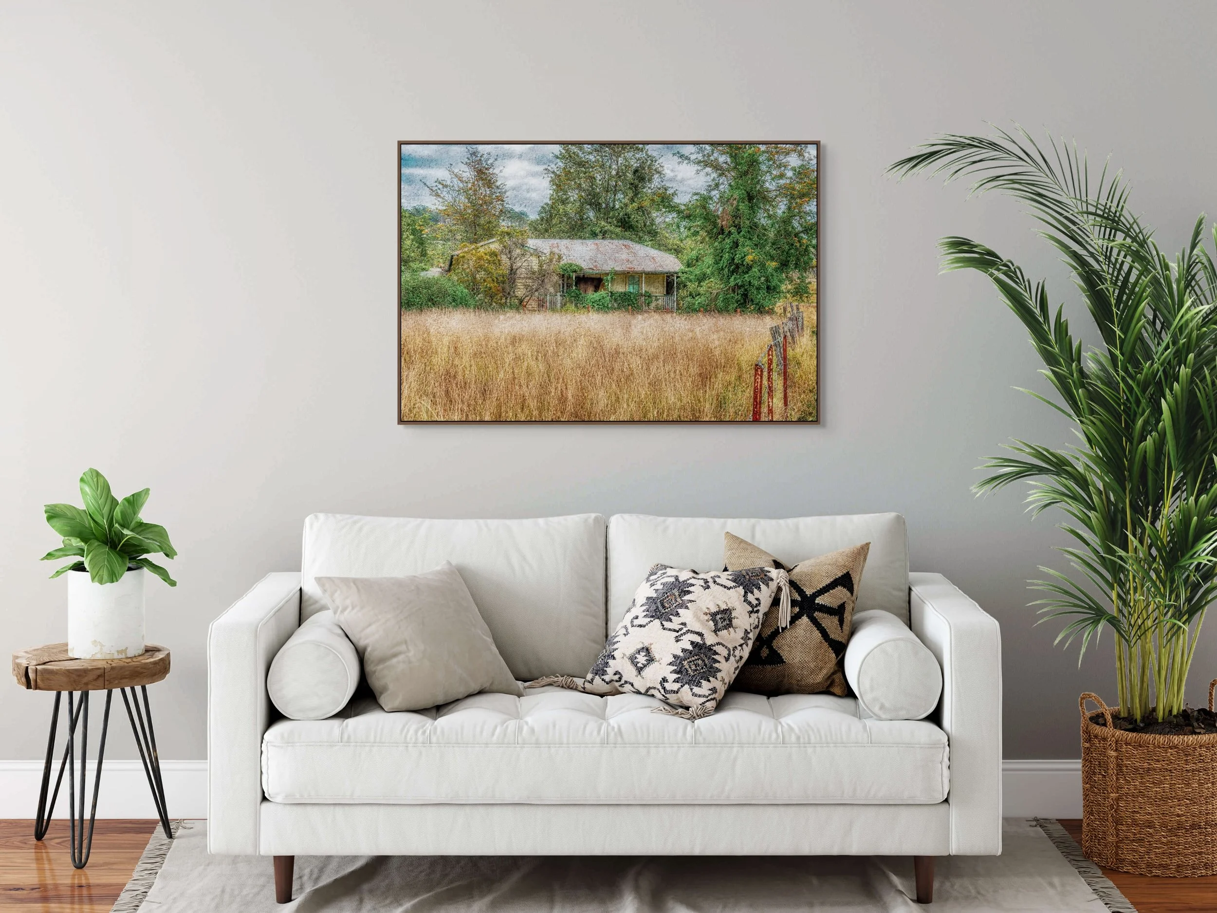 Old abandoned farmhouse surrounded by tall grass and trees in rural landscape.