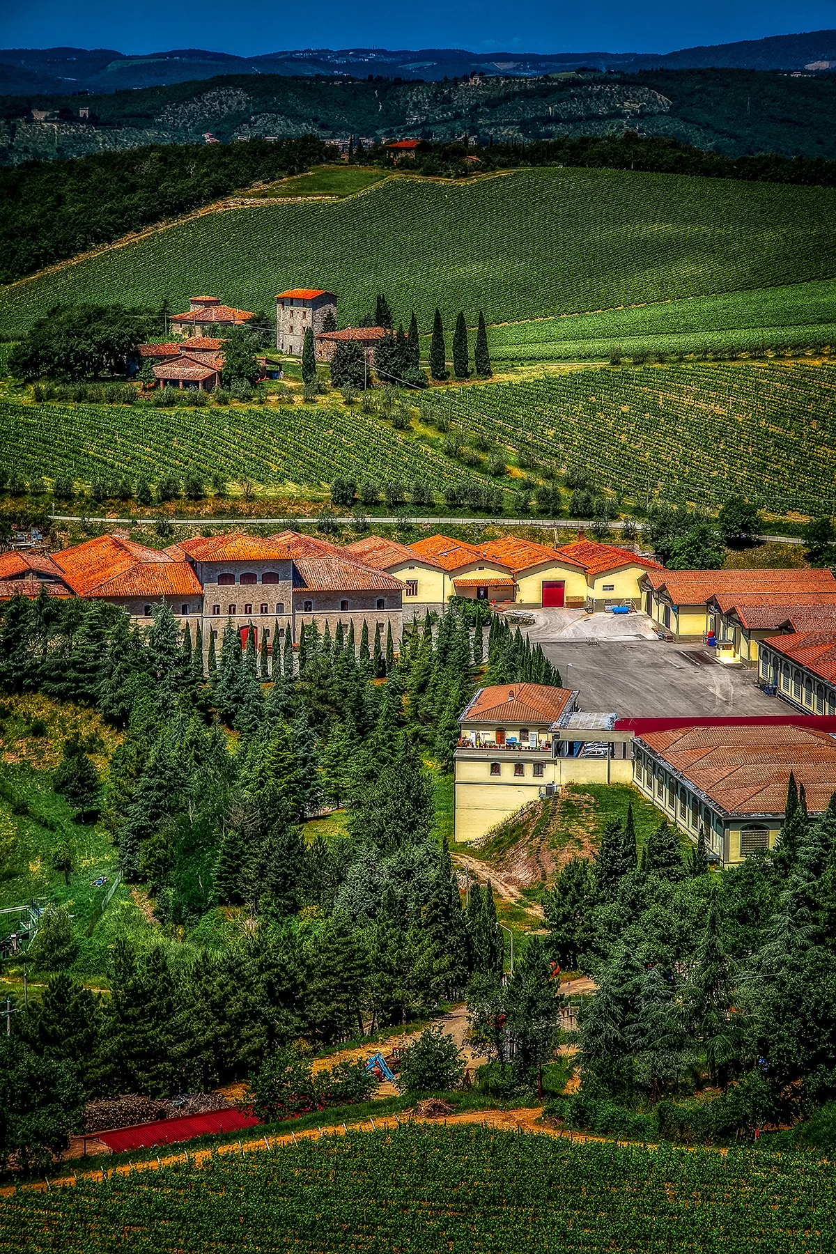 Rolling vineyards and terracotta-roofed buildings in the hills of Tuscany.