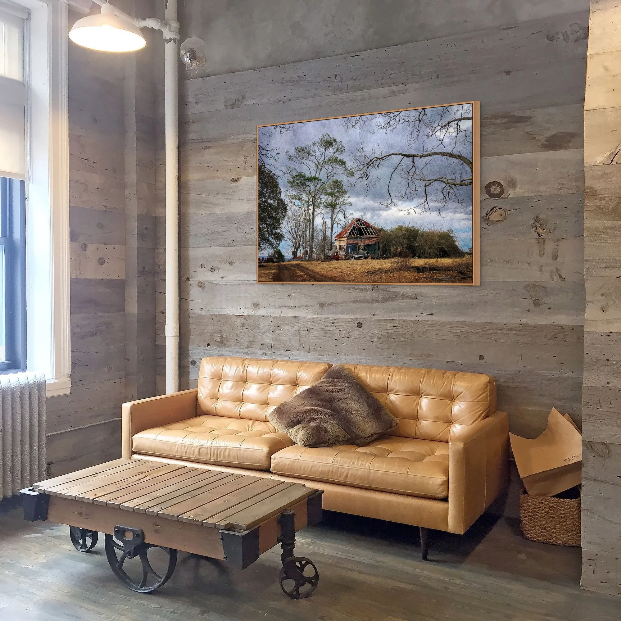 Abandoned rustic farmhouse beside a dirt road in a rural countryside landscape.