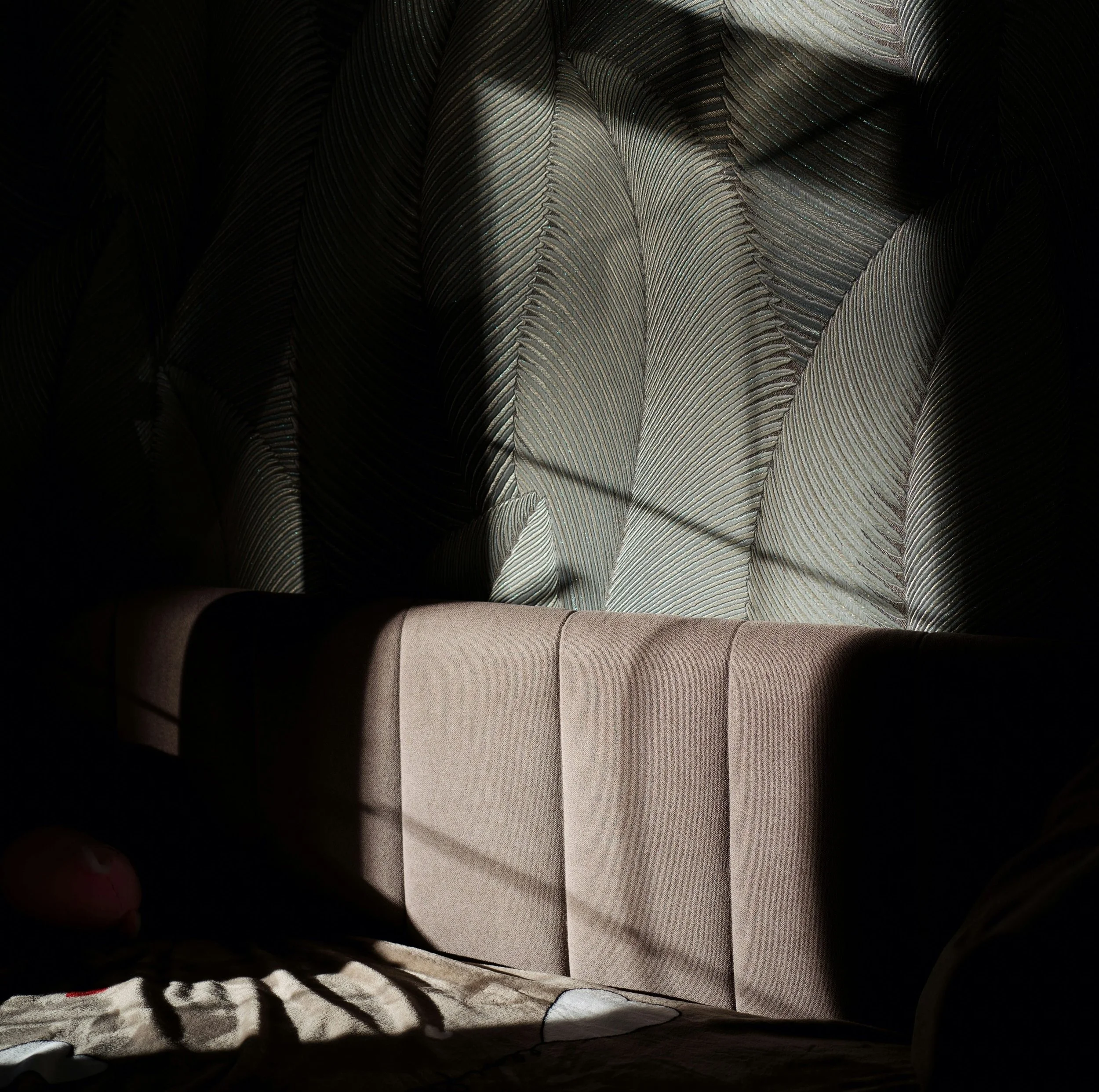 Bedroom detail with upholstered headboard and textured wallpaper reflecting refined bespoke interior design