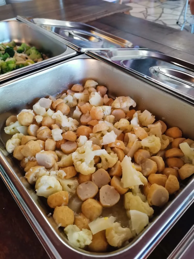 Chafing dish filled with cauliflower, chickpeas, and sliced sausages.