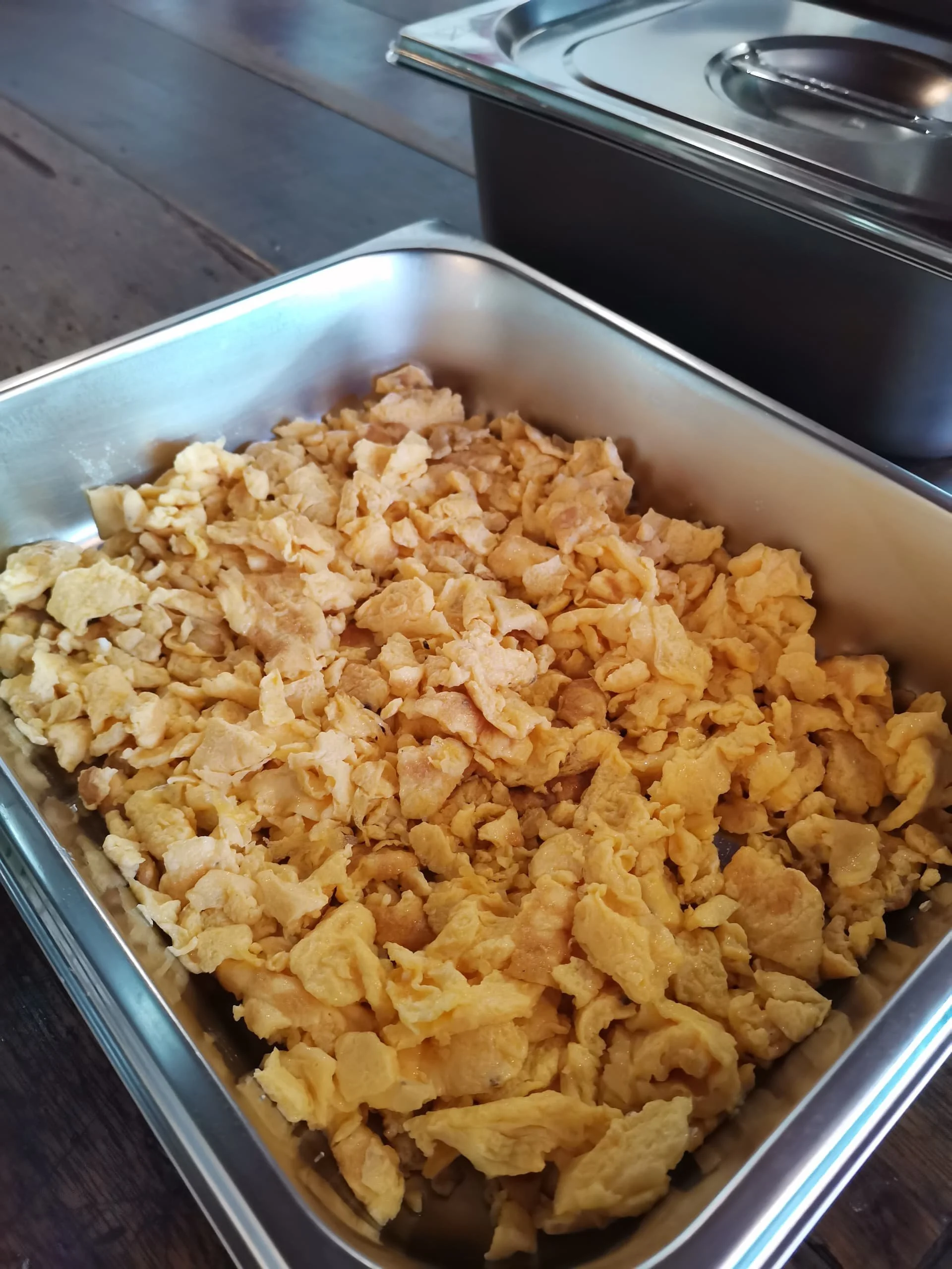 Scrambled eggs in a stainless steel serving tray.