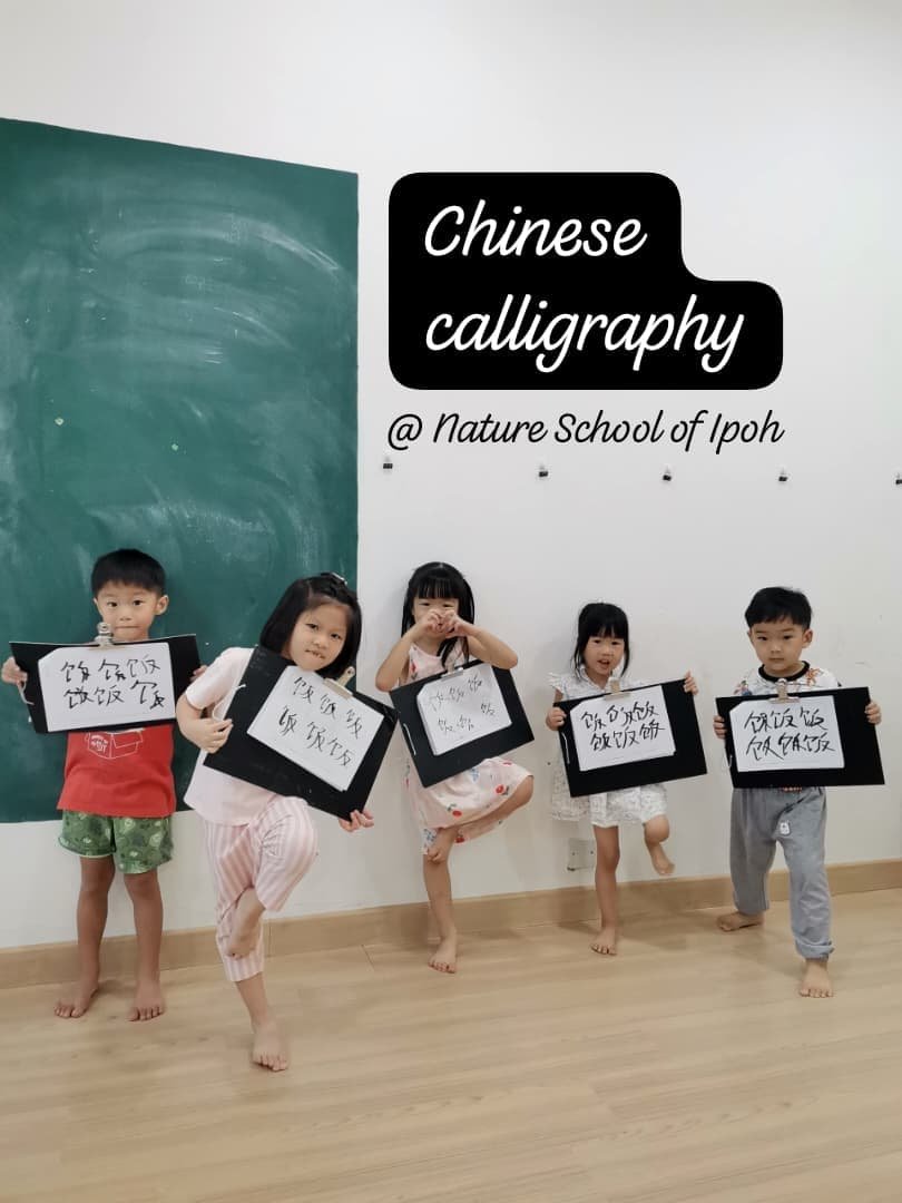 Five children standing in front of a wall, holding blackboards with Chinese calligraphy, at a nature school.