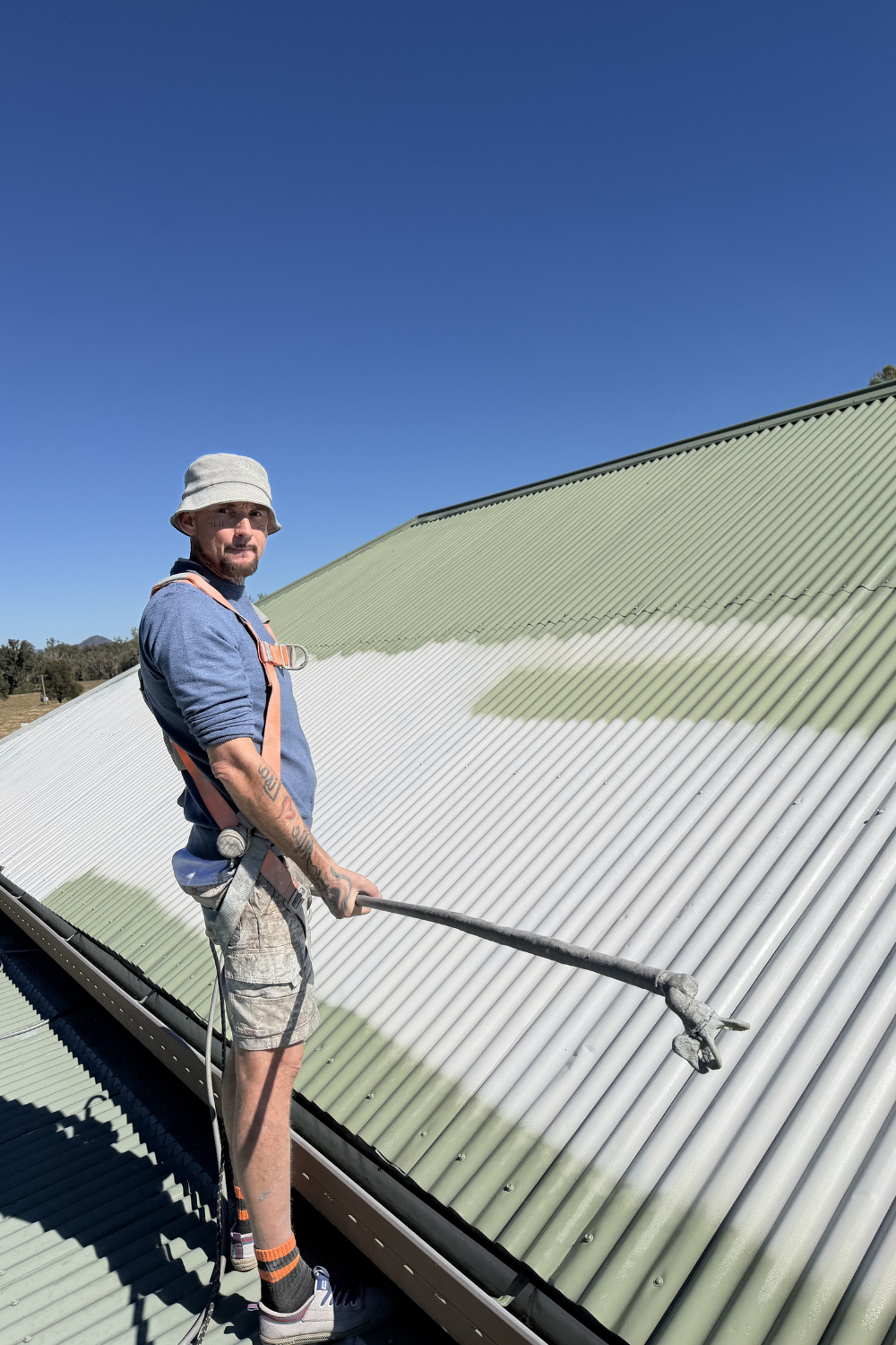 Alfie Hendry of Hendry’s Restorations spray painting a roof green in Sapphire Central