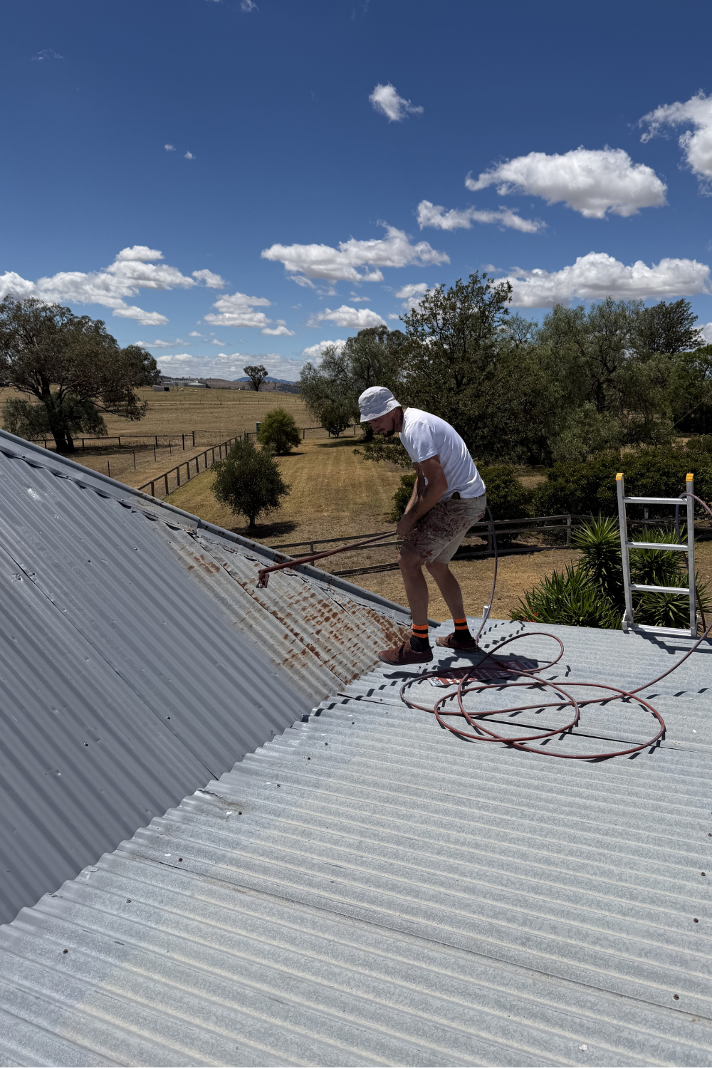 Alfie Hendry of Hendry’s Restorations. spray painting a metal roof in Emerald, Queensland.