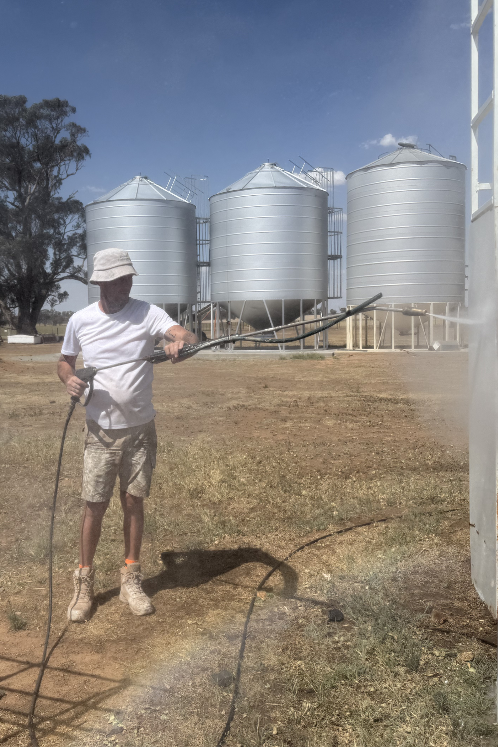 Alfie Hendry a roof painter in Willows, Queensland on a farm painting a farm silo.