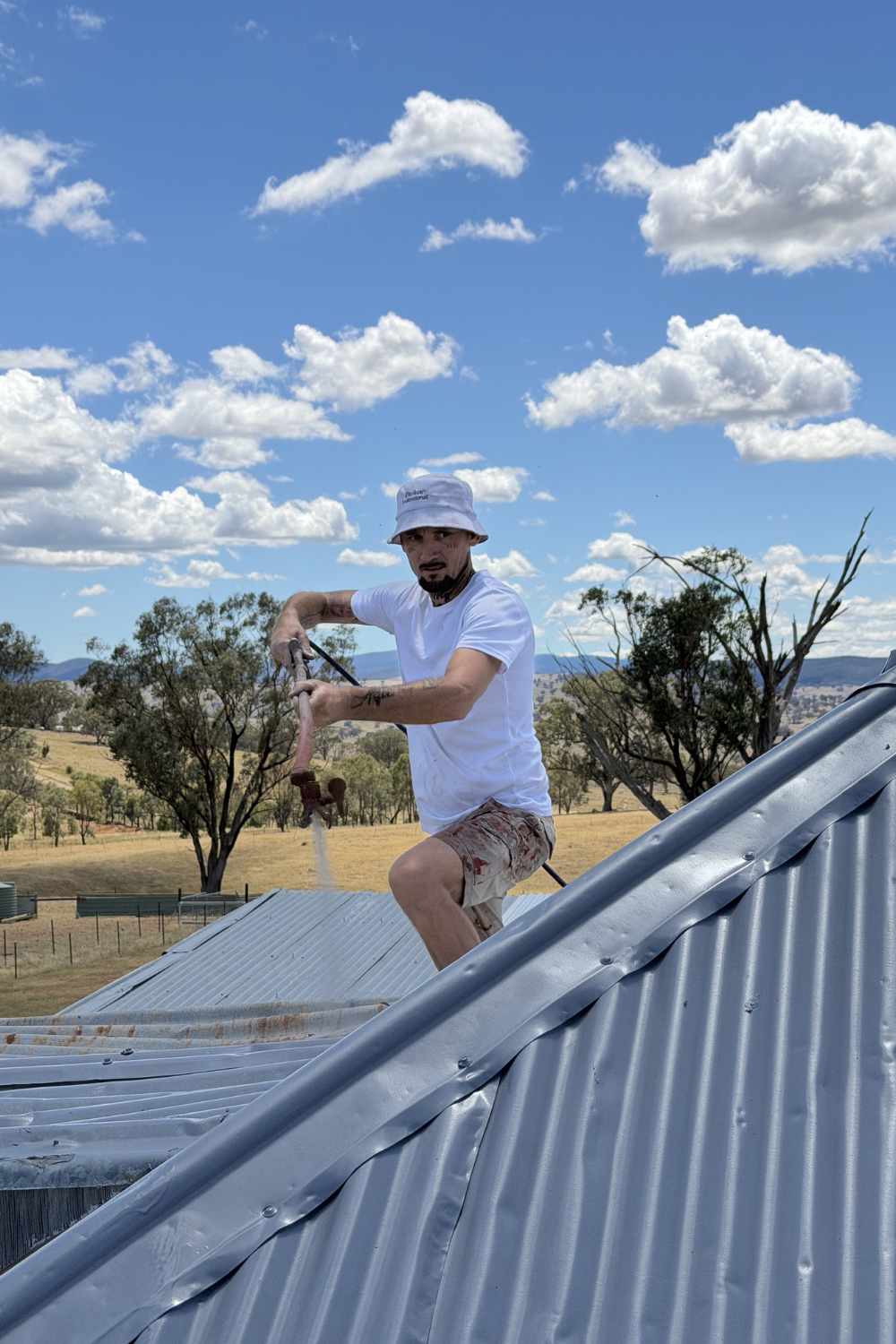 Alfie Hendry spray painting a roof in Banana, Queensland.