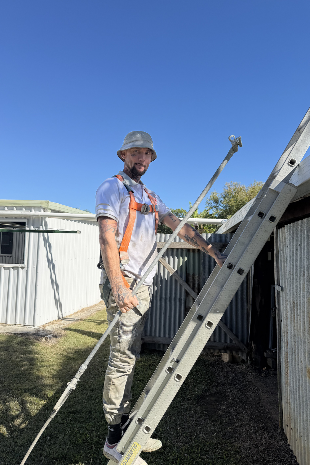 A roof painter with a spray gun standing on a ladder near Arcadia Valley, Queensland.