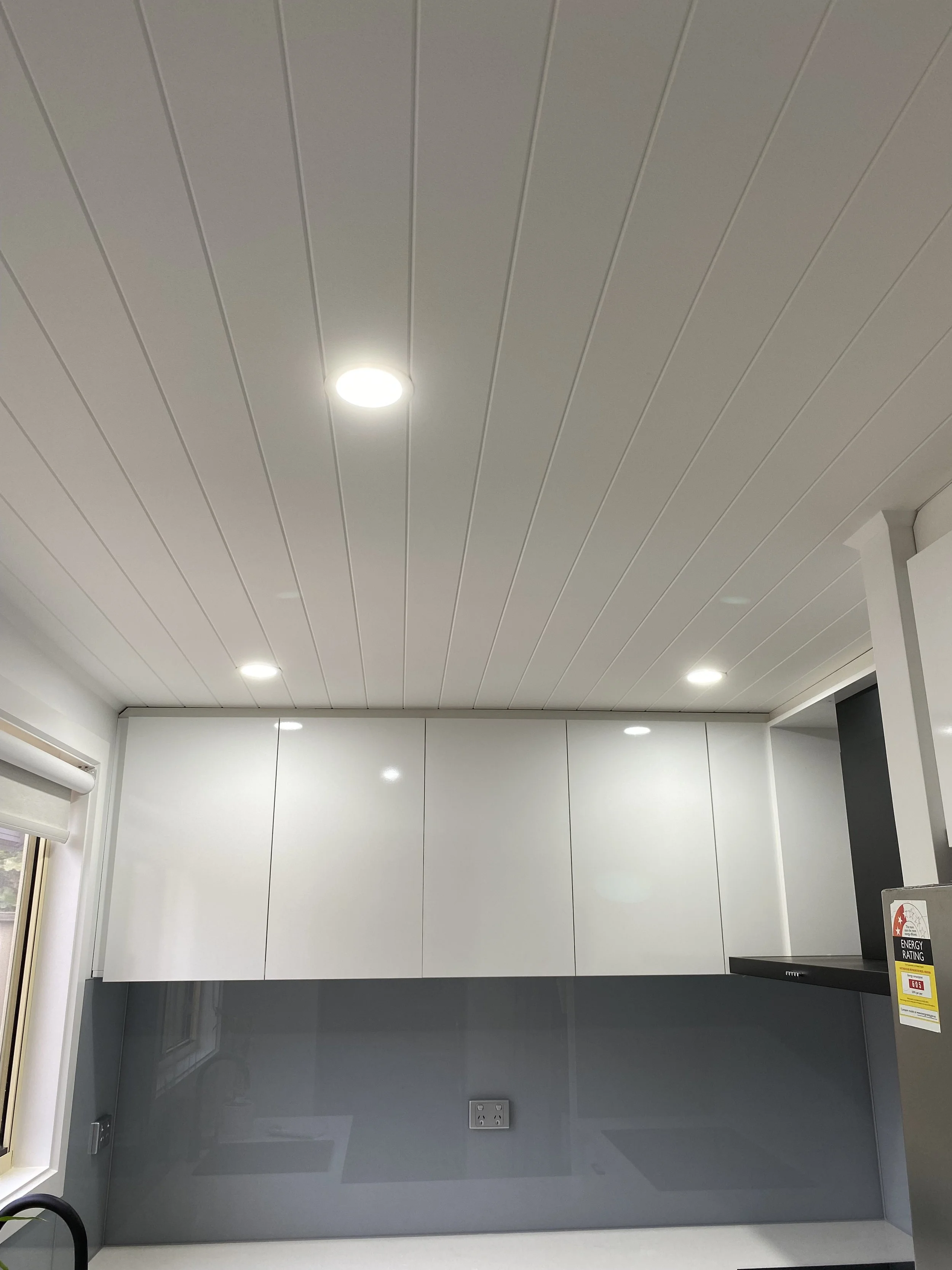 Modern kitchen ceiling with recessed lighting, white cabinets, and a light blue wall below the cabinets.