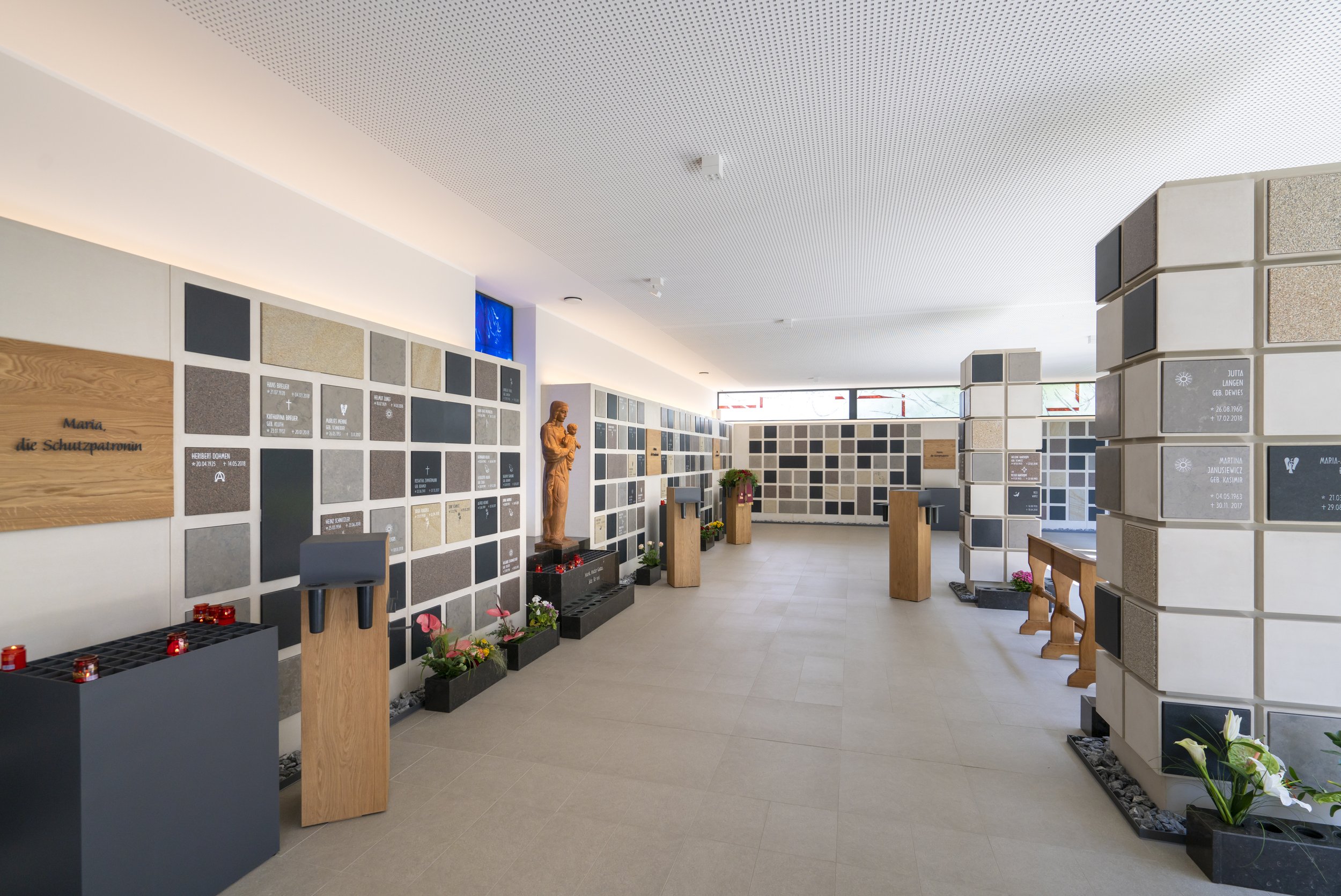 Urnenkammern von Schneider Kunstgestein im Innenraum einer Gedenkstätte mit Blumen.