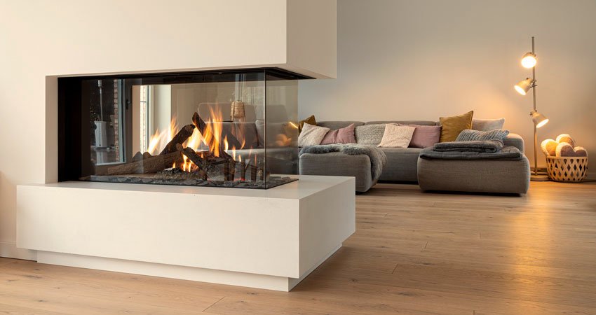Moderner Wohnraum mit Kamin, graues Sofa mit Kissen, Holzfußboden, Stehlampe mit mehreren Lichtquellen, dekorativer Korb mit Gegenständen