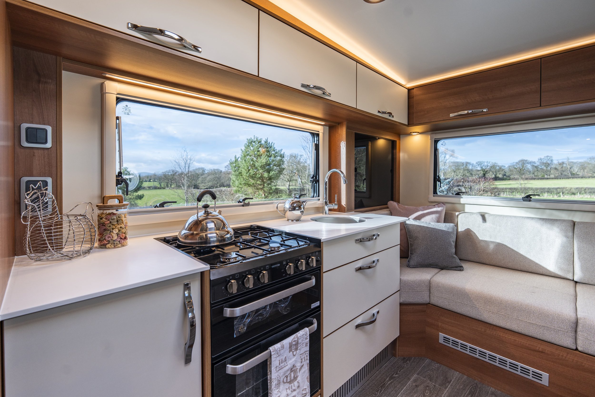 Interior of a modern RV with a kitchenette, dining area, and seating.