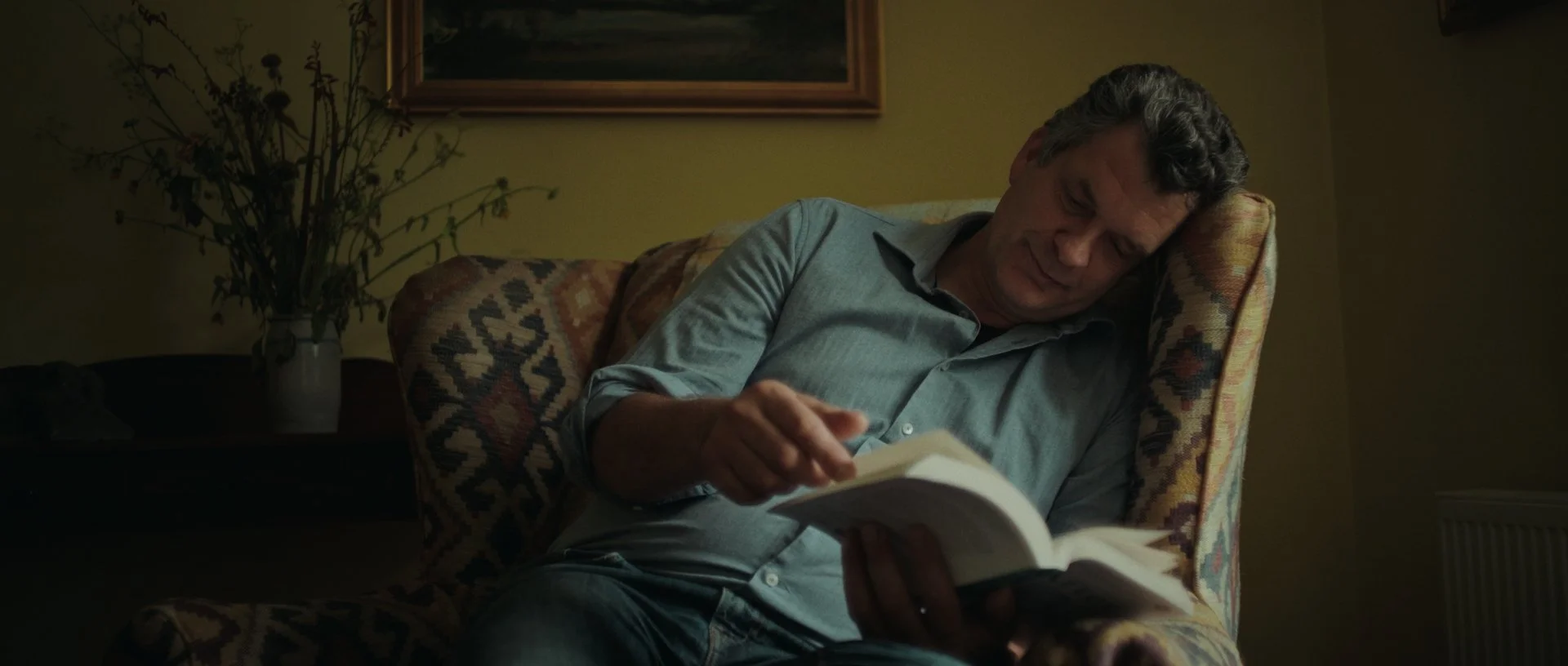 Wider angle of Jan-Jacob reading, shadows and highlights creating a cozy ambiance