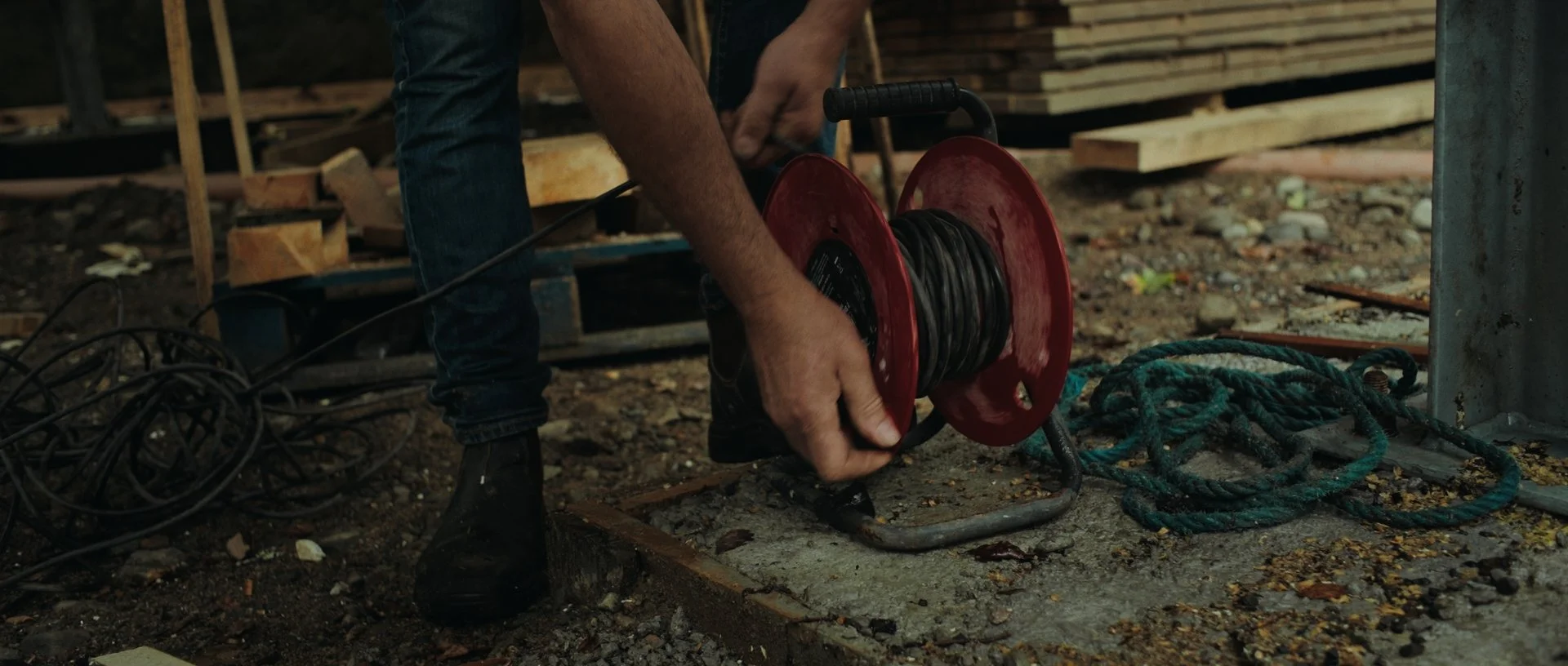 Jan-Jacob winding up a red electrical cable on the building site, the rich red adding a striking contrast
