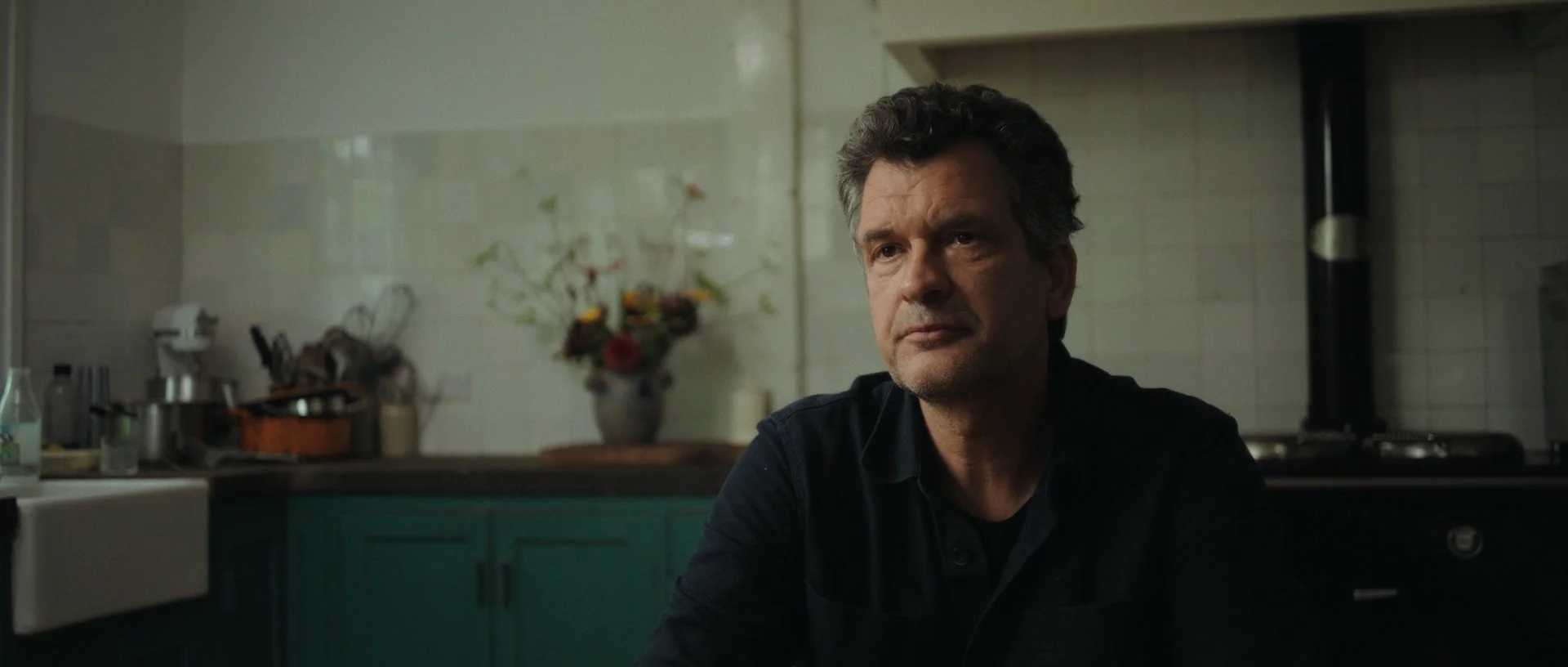 Jan Jacob in a warm, cinematic kitchen setting, discussing life with chronic Lyme disease, soft natural light enhancing textures