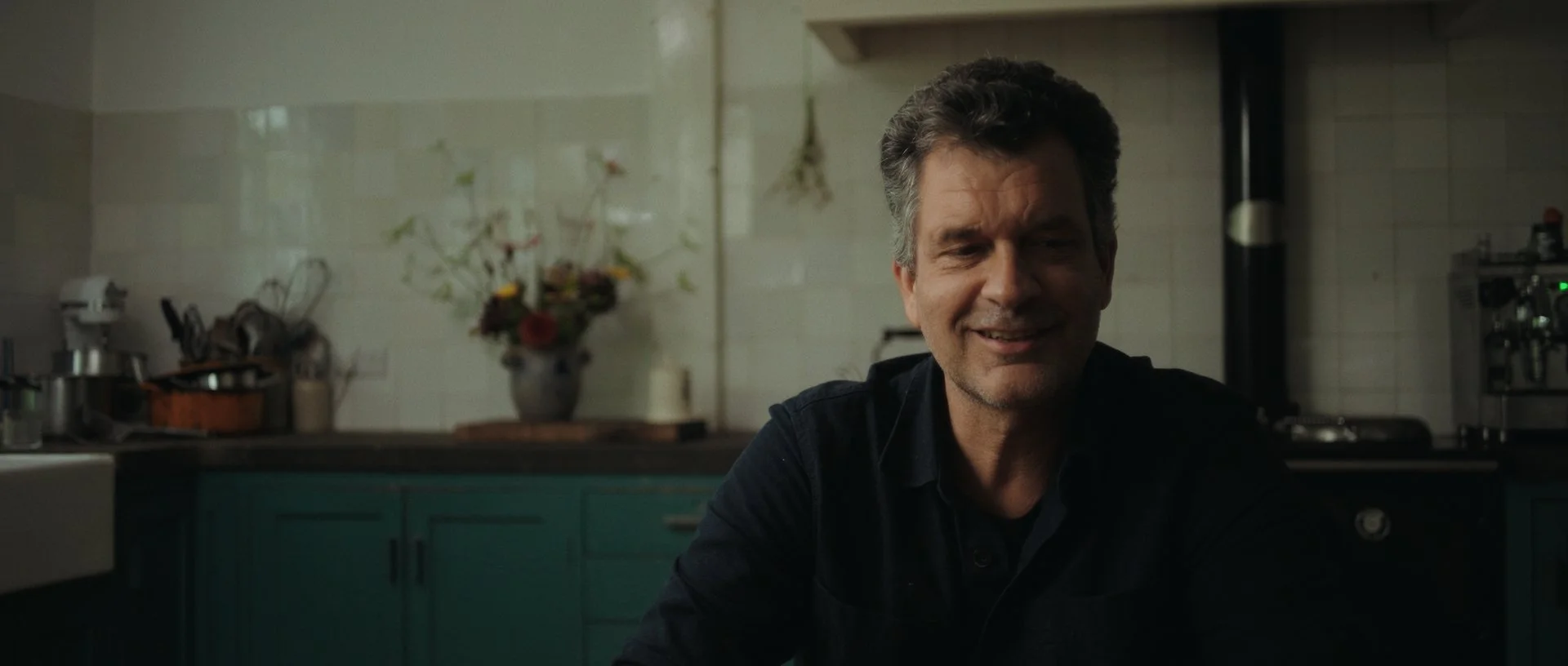 Another moment from the intimate interview scene, warm kitchen tones complementing his honesty and openness