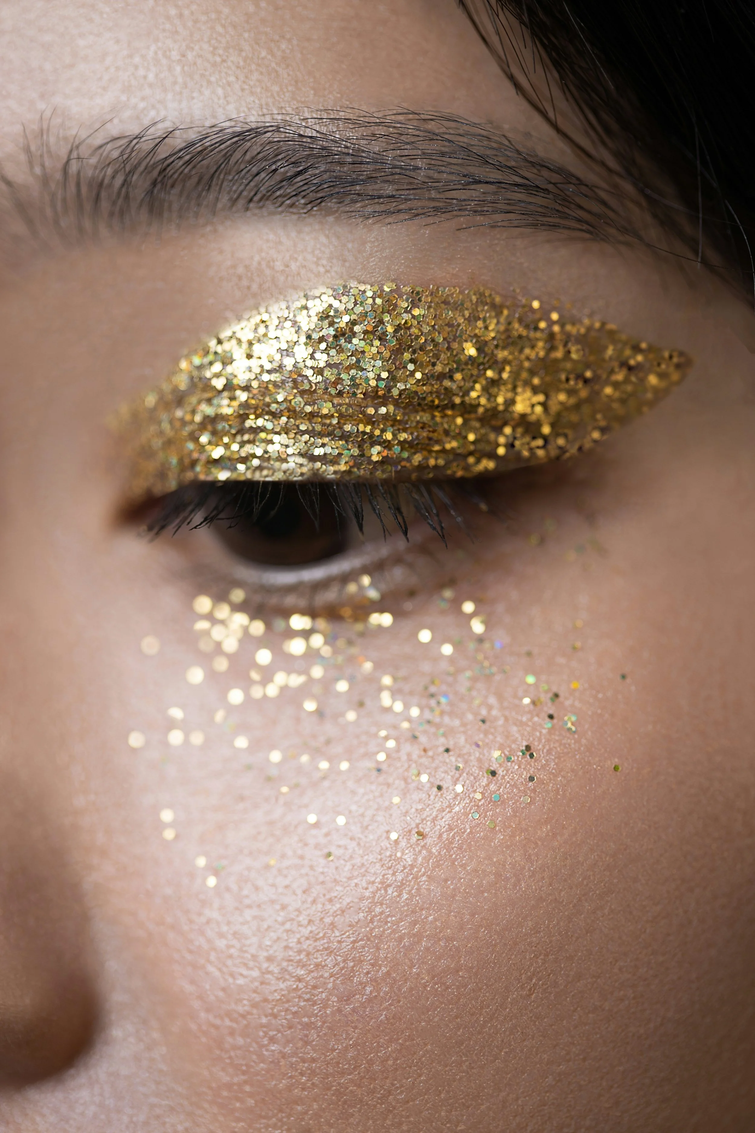 Zoom sur un maquillage avec du maquillage doré brillant appliqué sur la paupière d'une personne