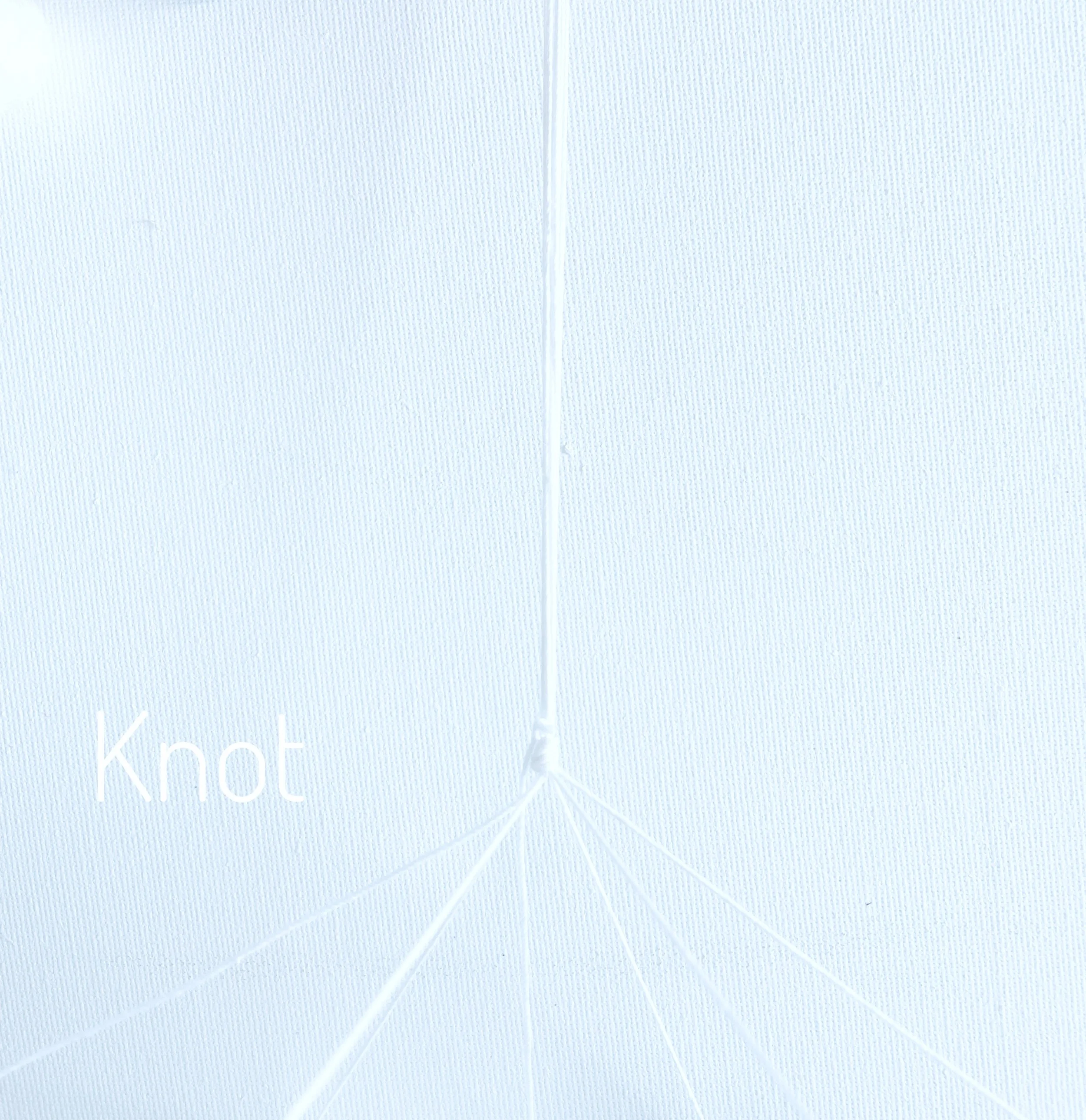 Six strands of white string attached to a wooden hoop and pulled together and knotted above hoop.