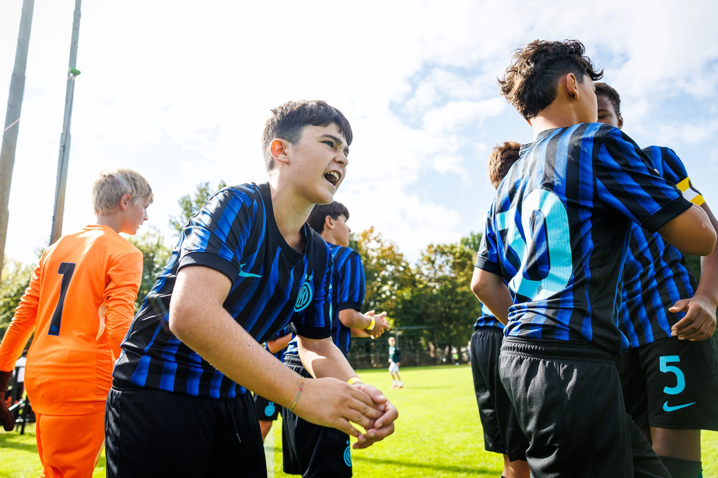 Youth soccer team in blue and black uniforms on a grassy field during daytime. During the Virgil's Legacy Trophy tournament in Tilburg.