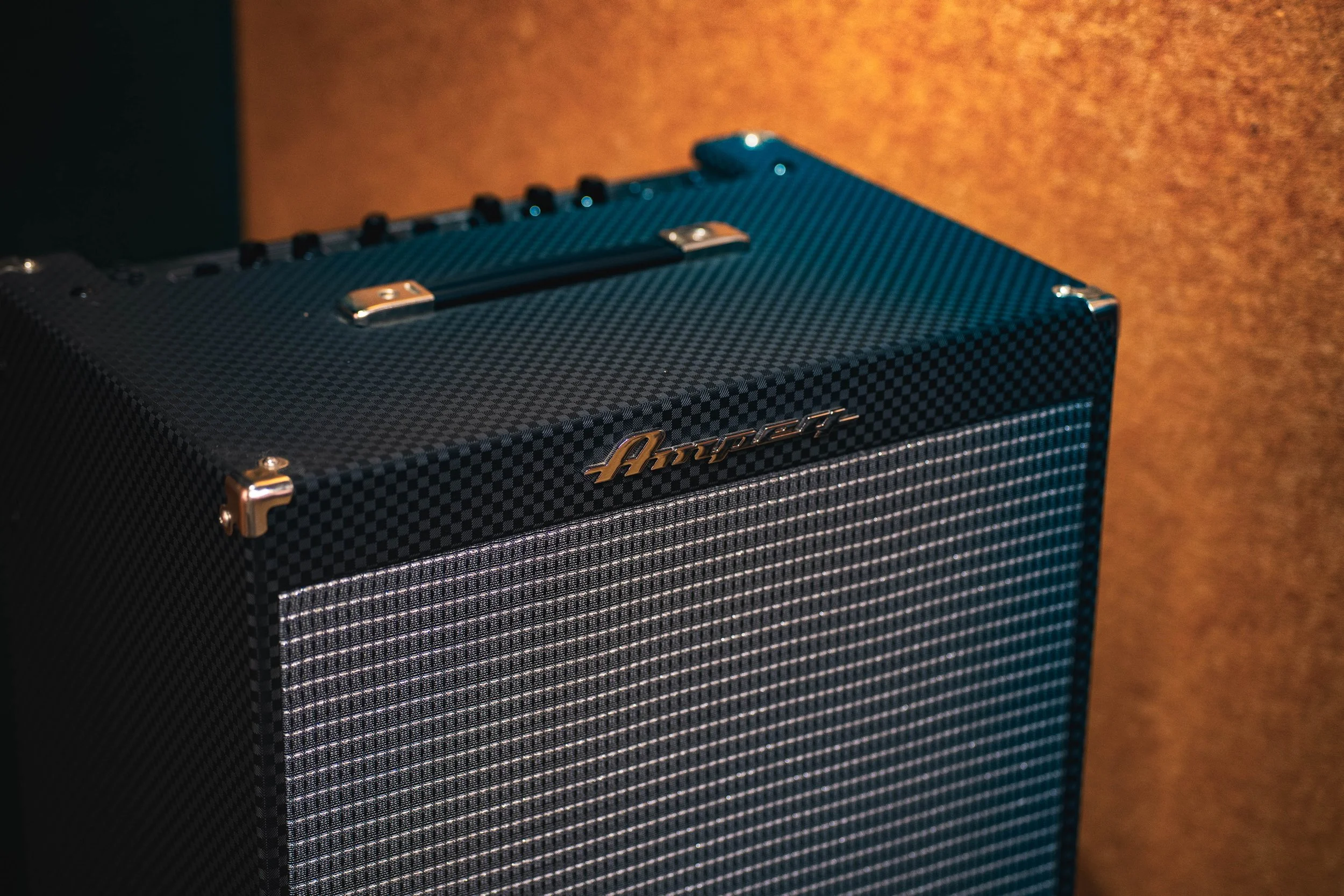 A close-up of a black guitar amplifier with a textured surface, metal corner protectors, and the brand name 'Ampeg' on the front.