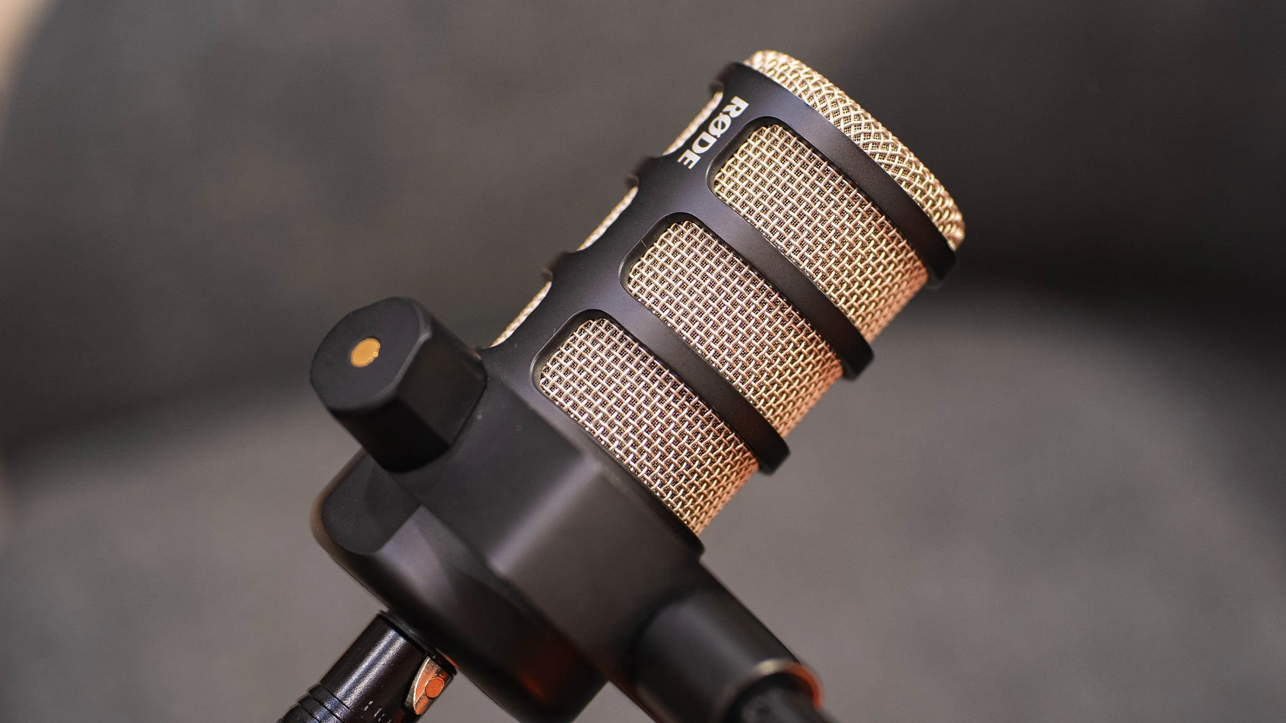 Close-up of a microphone with a metallic grille and black body against a dark background.
