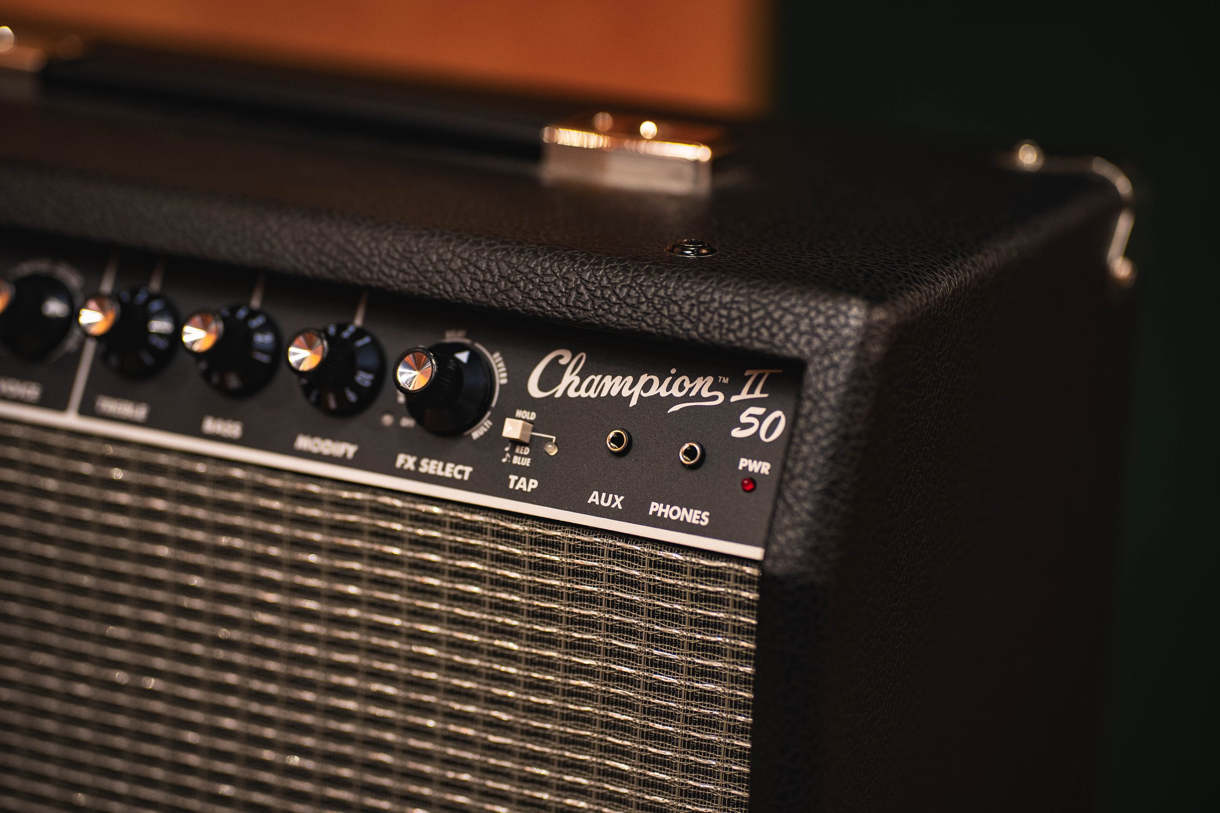 Close-up of a Fender Champion II 50 guitar amplifier, showing control knobs, input jacks, and textured black casing.
