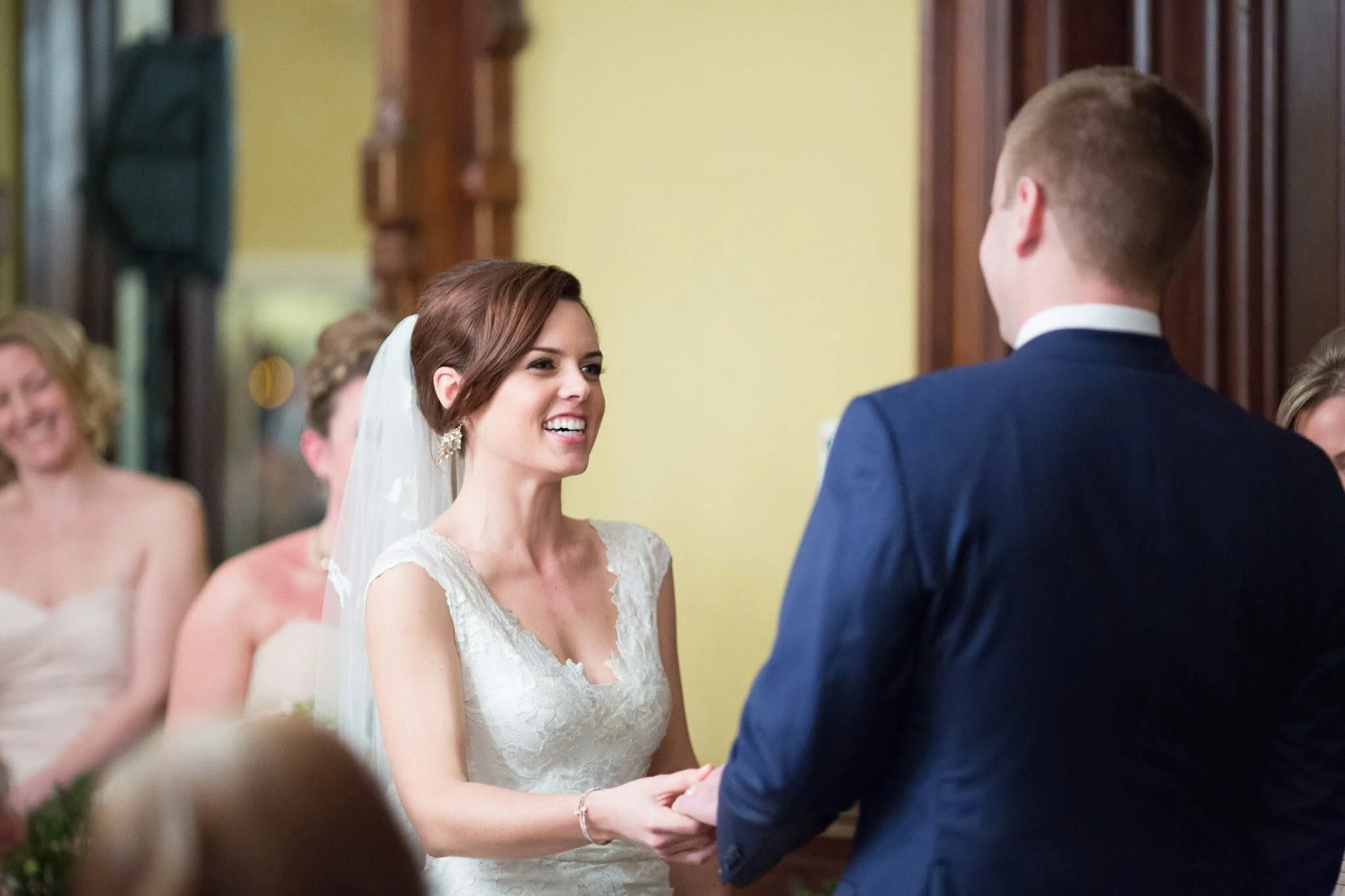 Bride and groom exchanging vows during wedding ceremony with bridesmaids in the background.