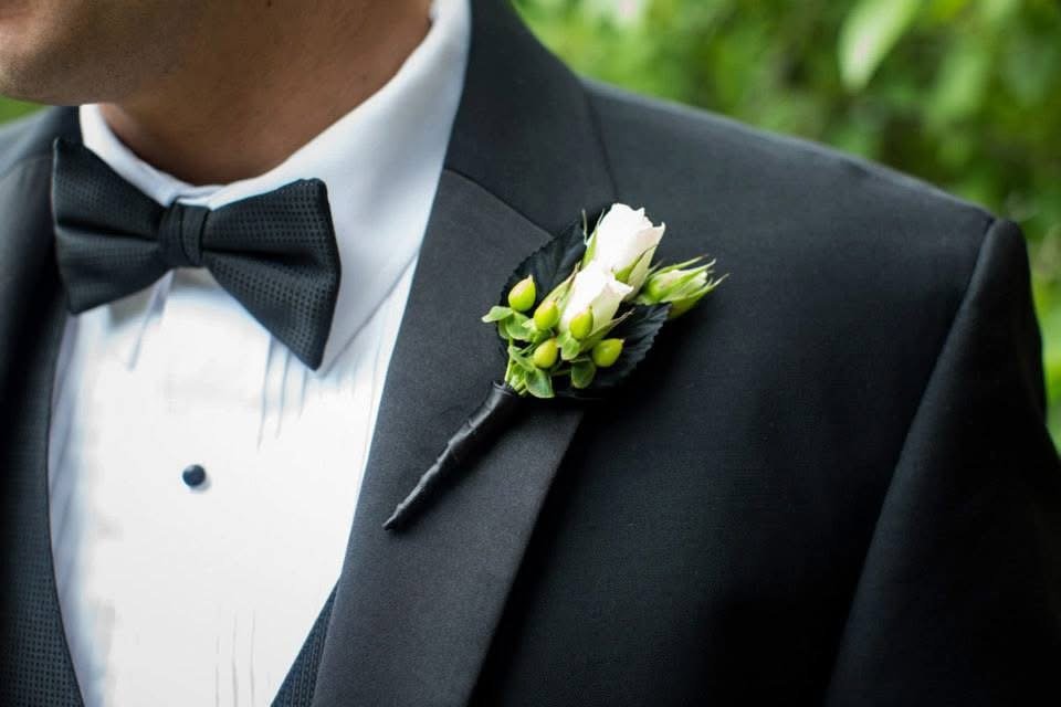 Man wearing a black tuxedo with a bow tie and boutonniere