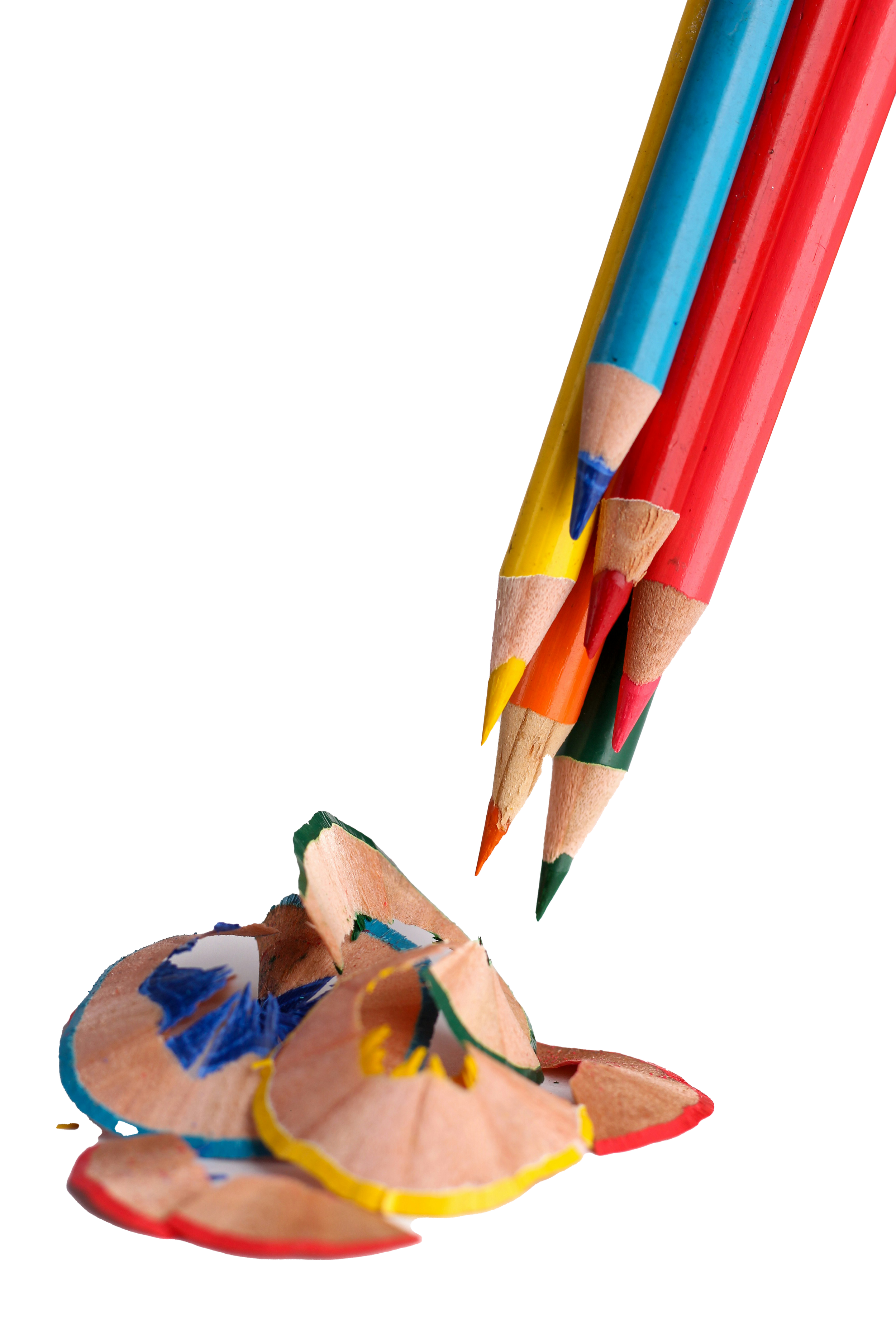 Colorful pencils with sharpened tips pointing downward, arranged above scattered pencil shavings, on a black background.