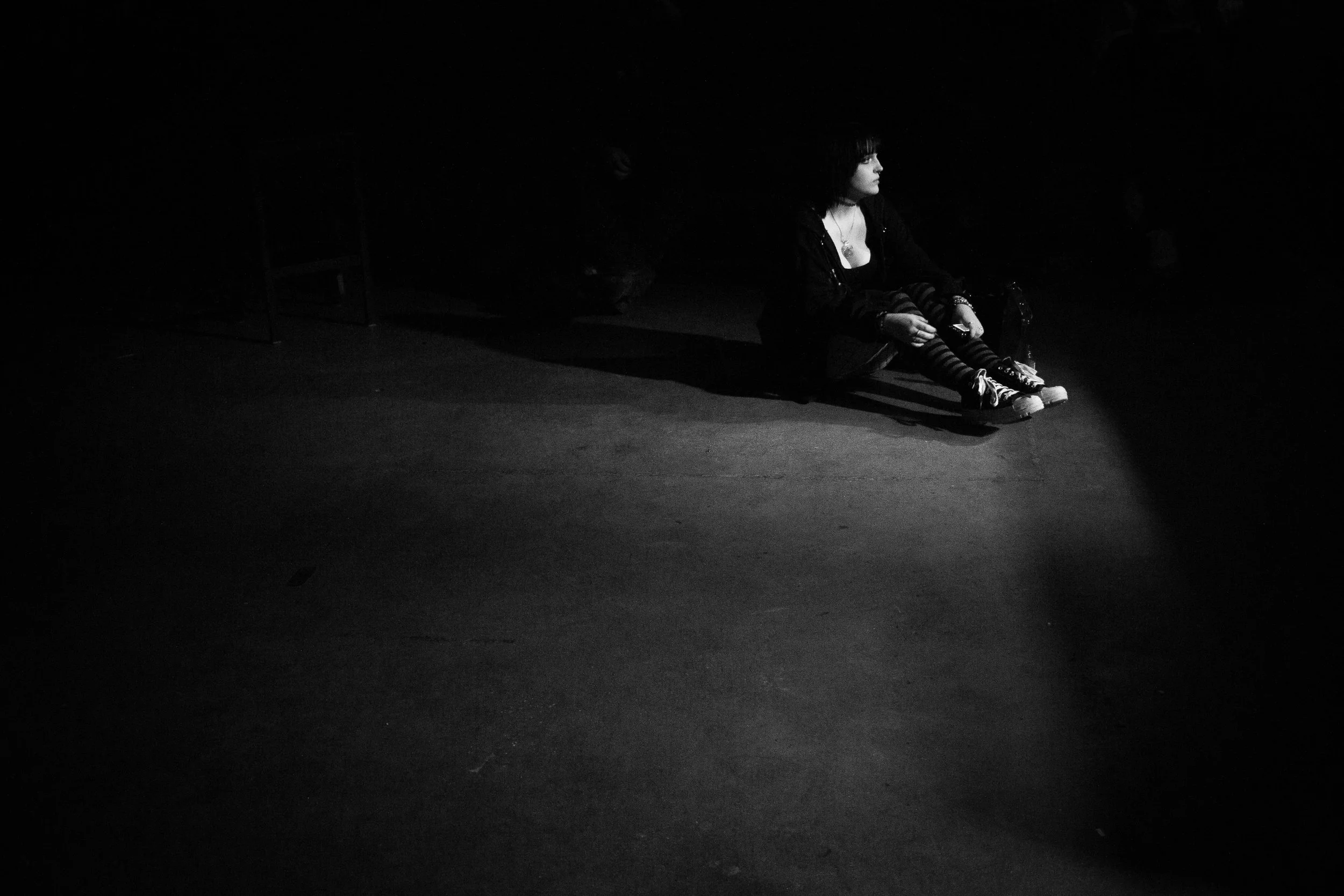 A woman sits on the floor at Rubber Gloves Rehearsal Studio waiting for a concert to start on Feb 29, 2024.