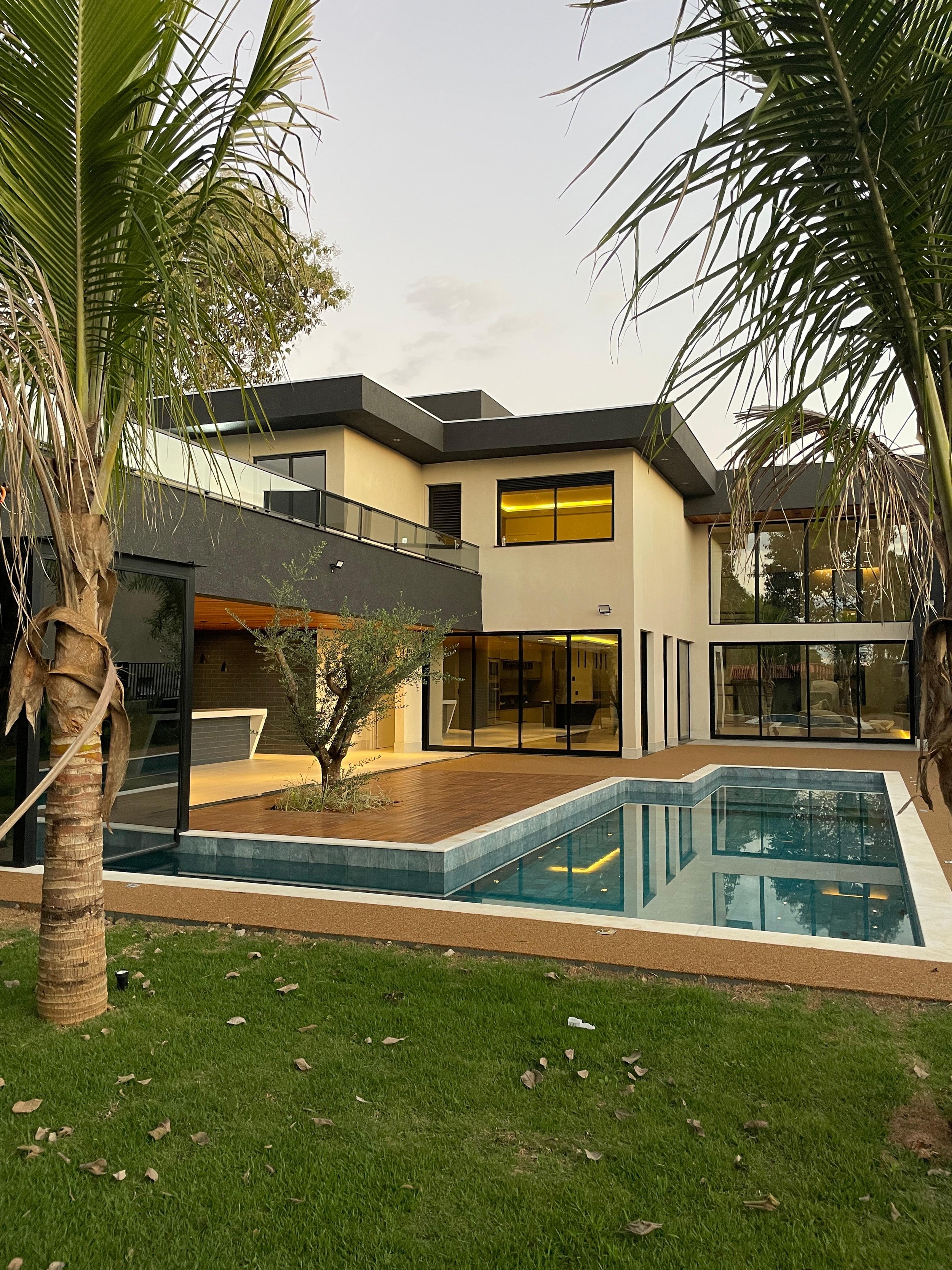 fachada da area gourmet com piscina integrada com sauna e palmeiras e oliveira Casa alto padrao em condominio de luxo bougainville